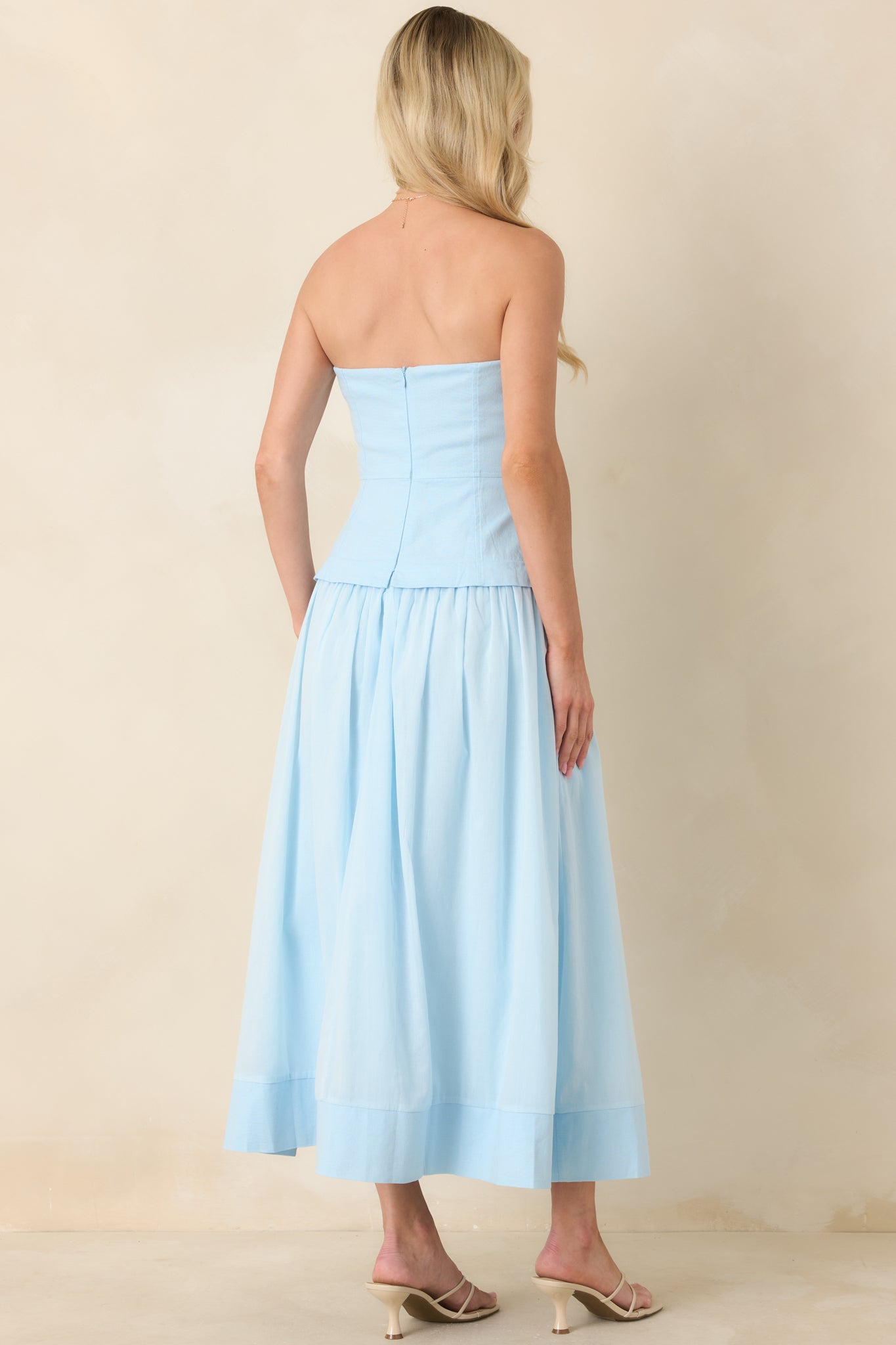 Rear view of the blue midi dress featuring a concealed zipper closure and clean seam detailing along the structured bodice.