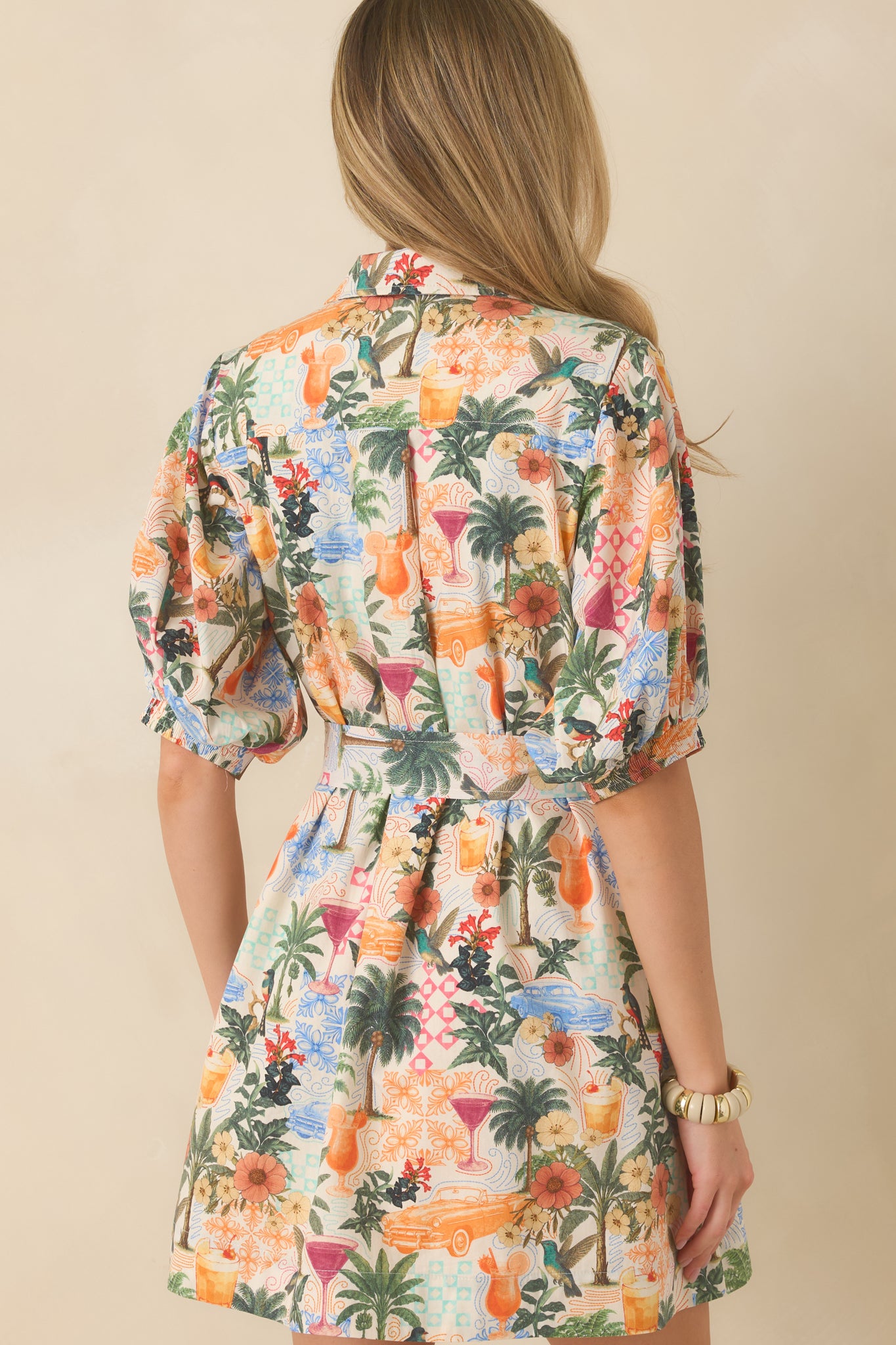 Rear view of multicolor mini shirt dress featuring a relaxed drape, elasticized puff sleeves, and defined waistline.