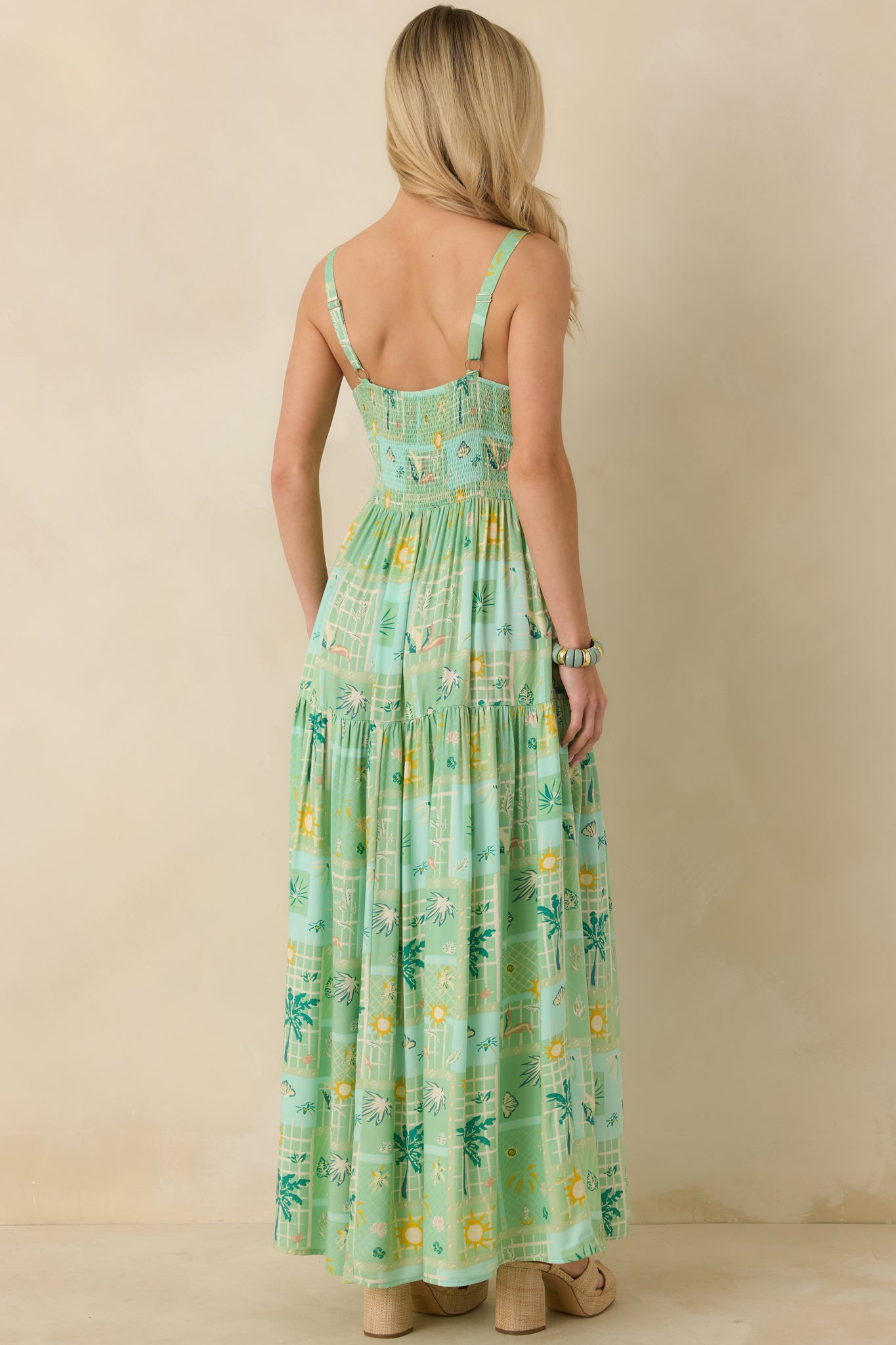 Rear view of green multicolor maxi dress featuring a smocked back panel and flowing tiered skirt.