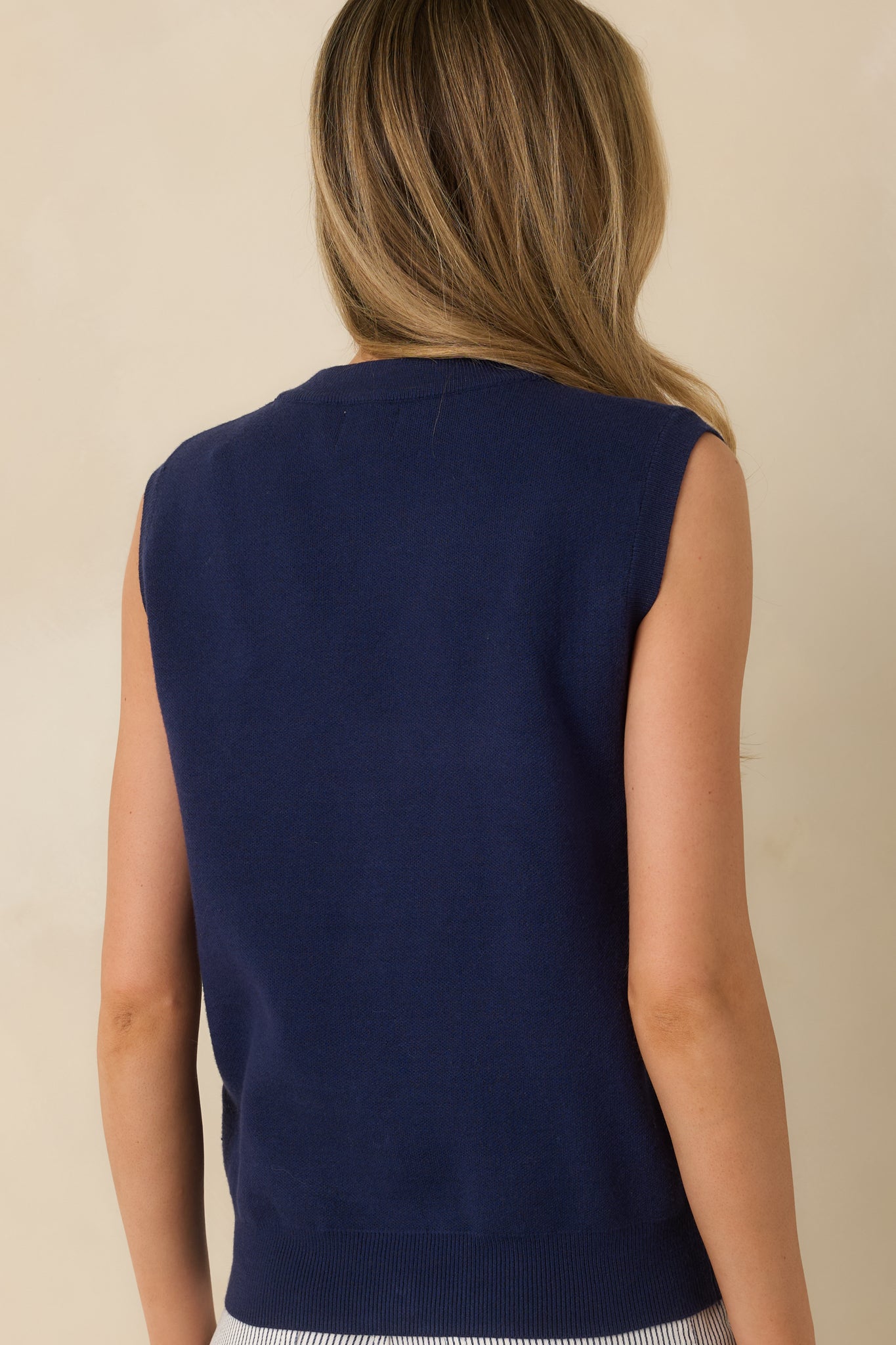 Rear view of the navy blue sleeveless sweater vest featuring a smooth knit finish and ribbed hem for a clean, structured look.

