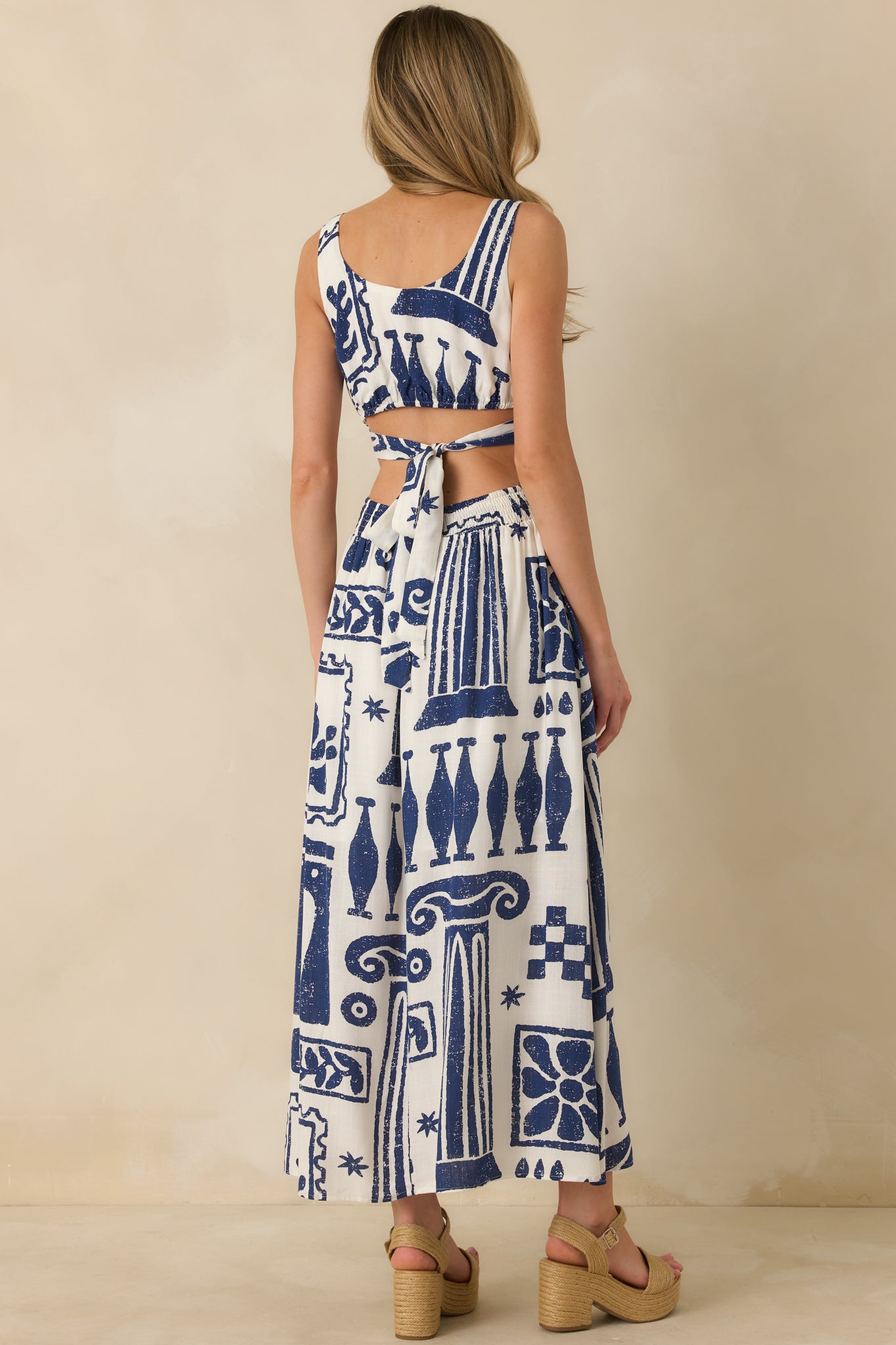 Rear view of navy and white maxi dress featuring adjustable tie-back closure and defined waist seam flowing into full skirt.