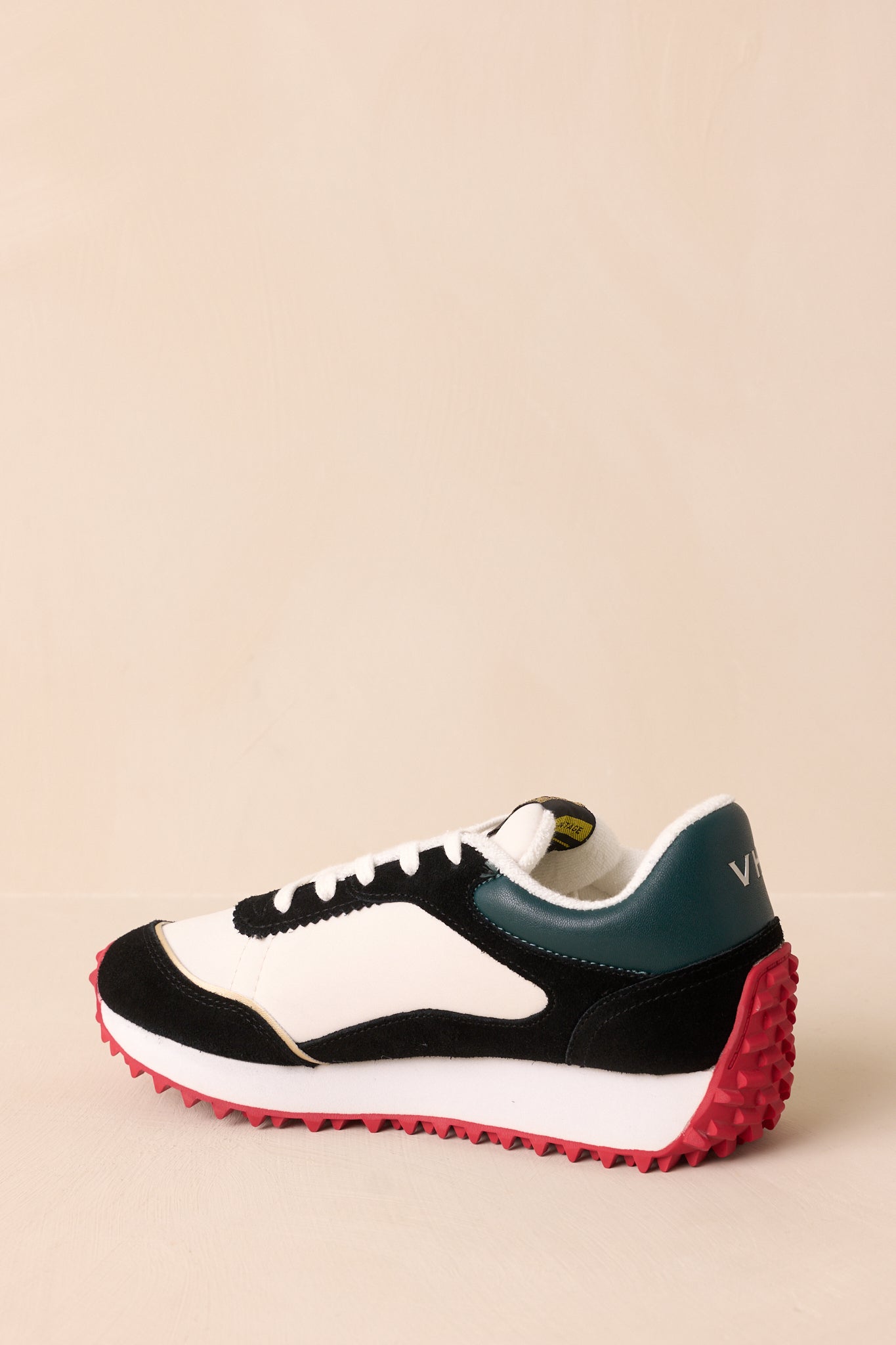 Rear view of the sneakers featuring the green heel panels and a glimpse of the red spiked sole.