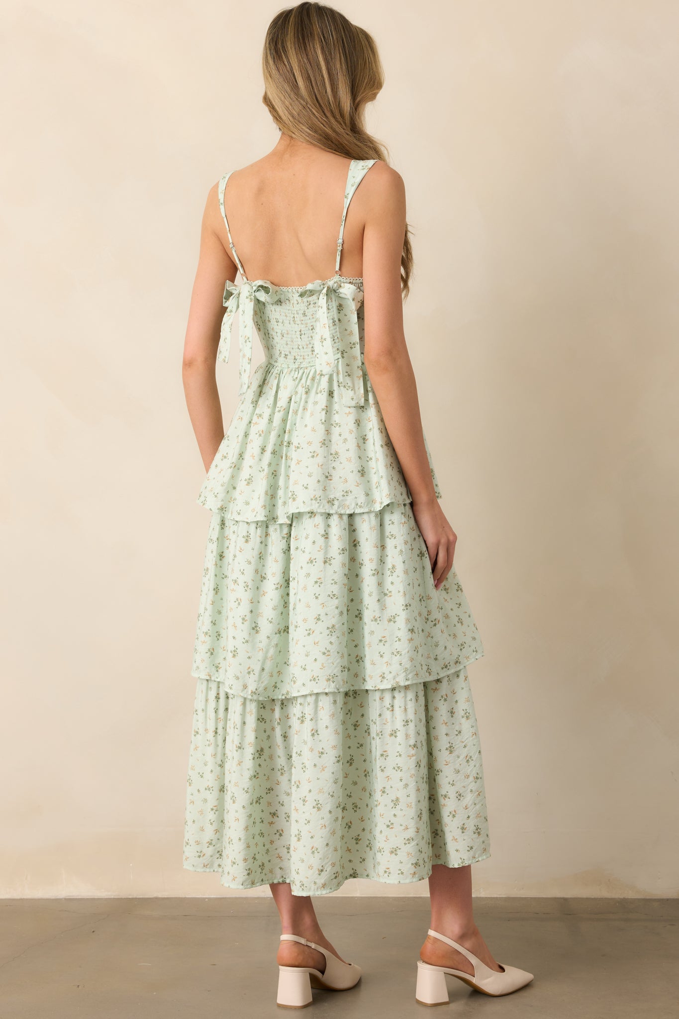 A rear view of the mint floral maxi dress, featuring two back bow details and a smocked back panel. The adjustable straps and tiered skirt complete the dress’s elegant design