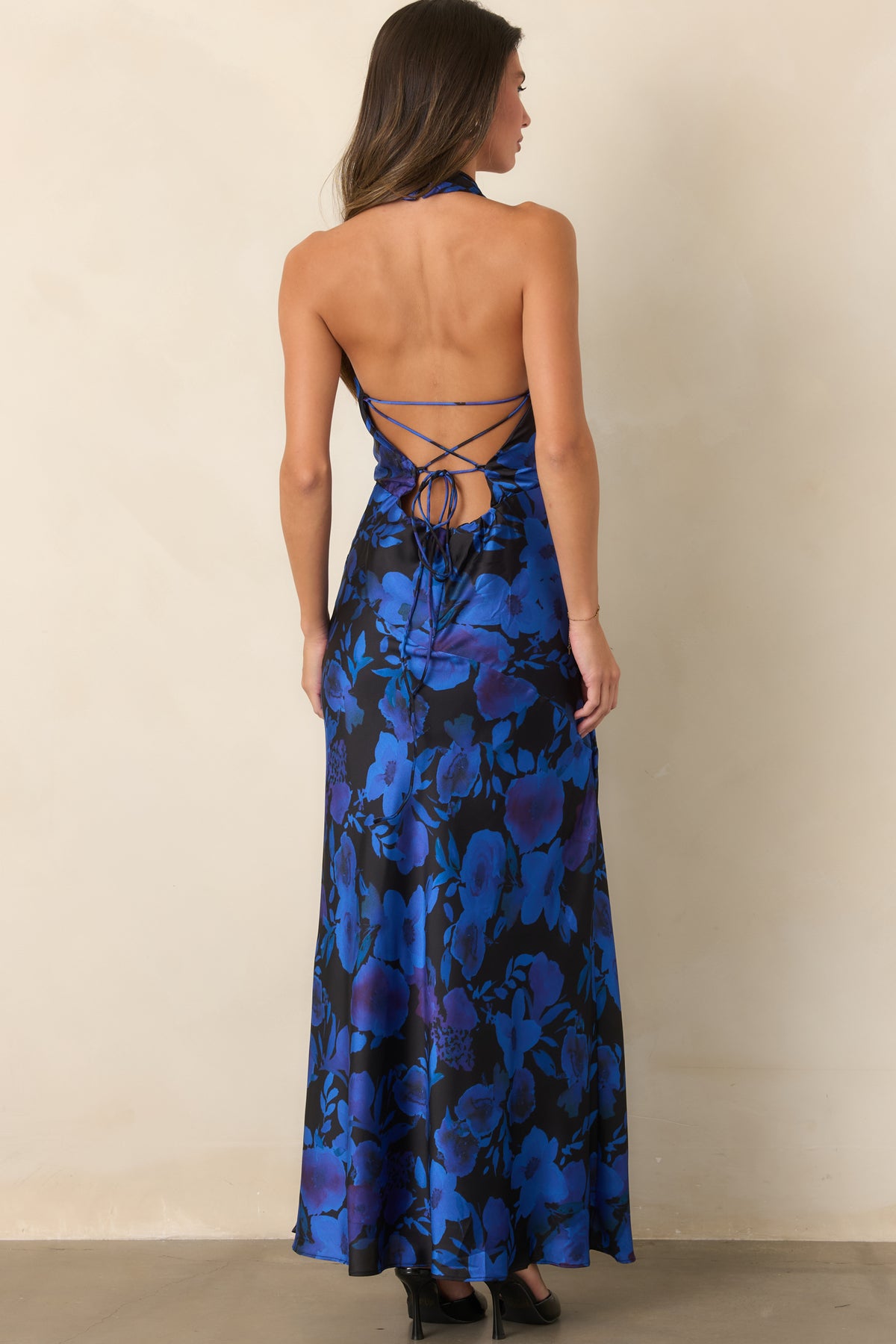 Rear view of the floral satin maxi dress showing the open back with adjustable crisscross lace-up ties and low zipper closure.