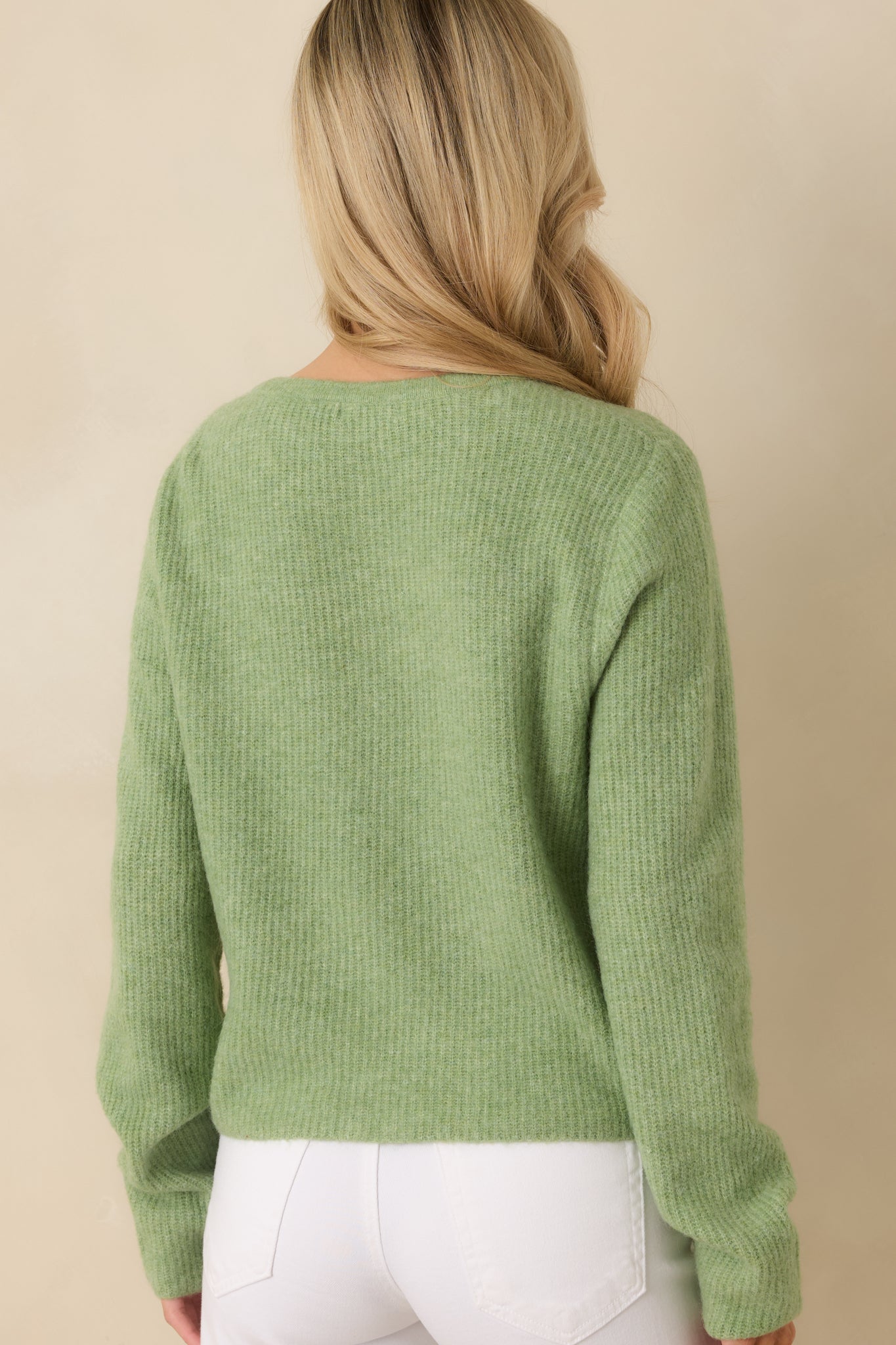 Rear view of green cardigan showing full length and slightly fitted shape.