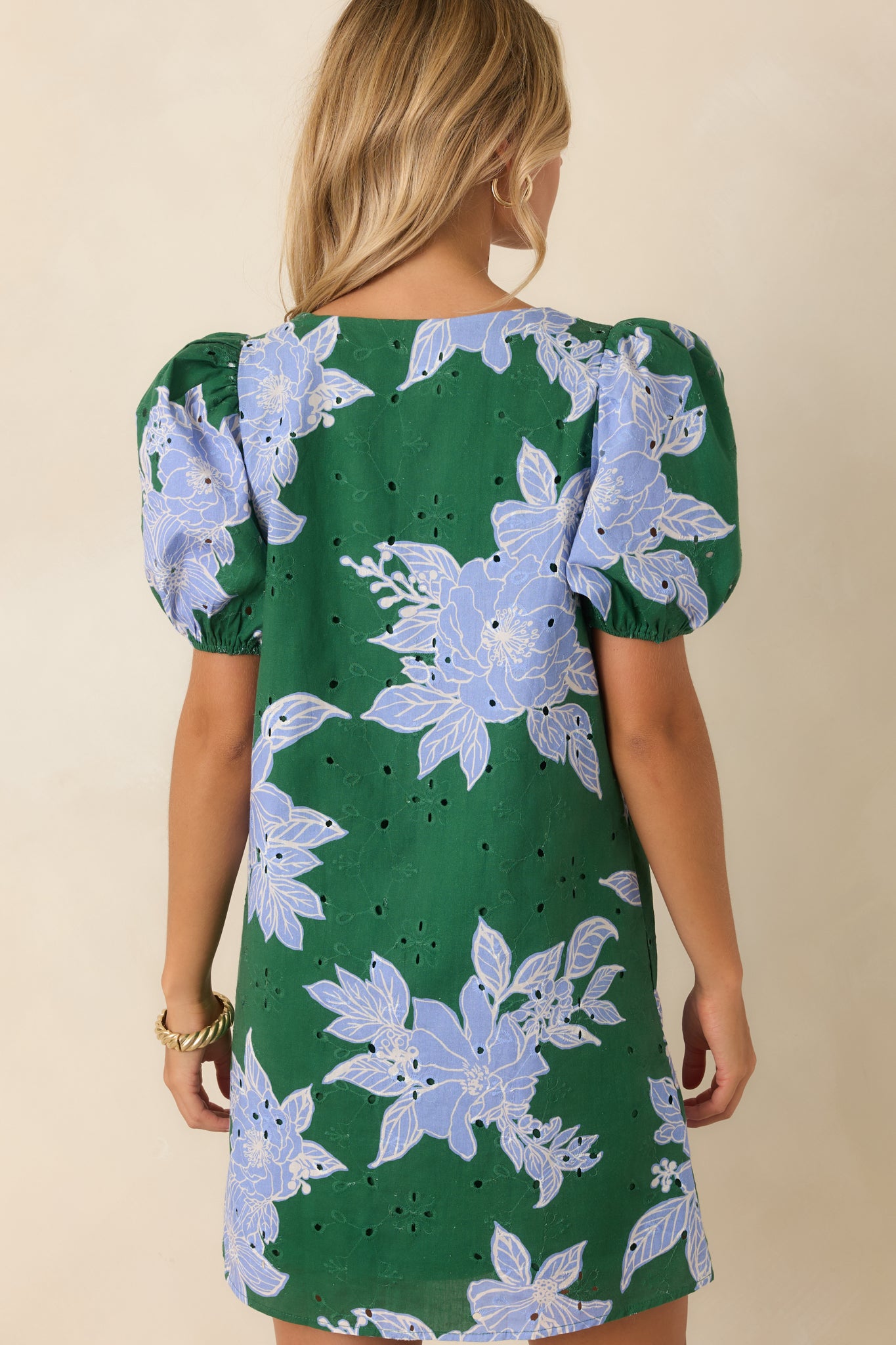 Rear view of the green cotton mini dress featuring a relaxed shift silhouette, eyelet embroidery, floral print, and lined design.