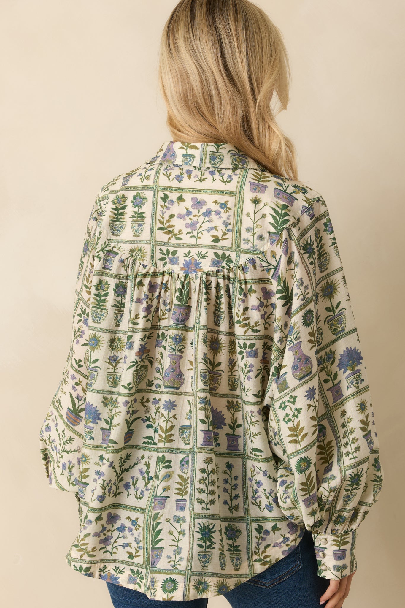 Rear view of the green floral blouse featuring a relaxed fit and long sleeves with buttoned cuffs.