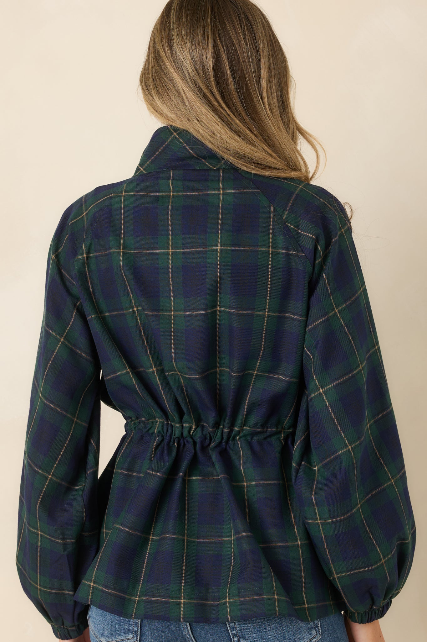 Rear view of the lightweight jacket featuring the green and navy plaid pattern, structured collar, long sleeves, elastic cuffs, and adjustable drawstring waist.
