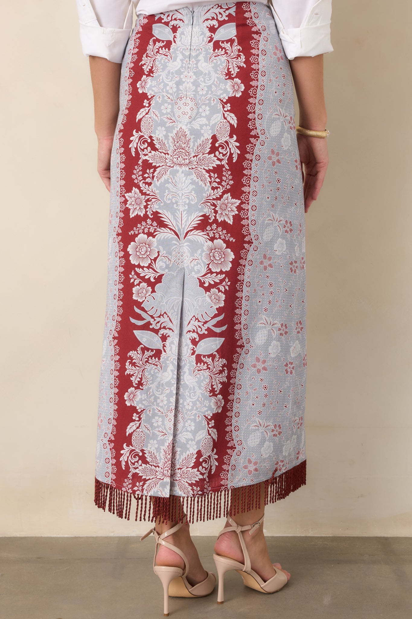 Rear view of the high-rise column skirt showing its clean concealed zipper, full lining, and fringe-finished hem.