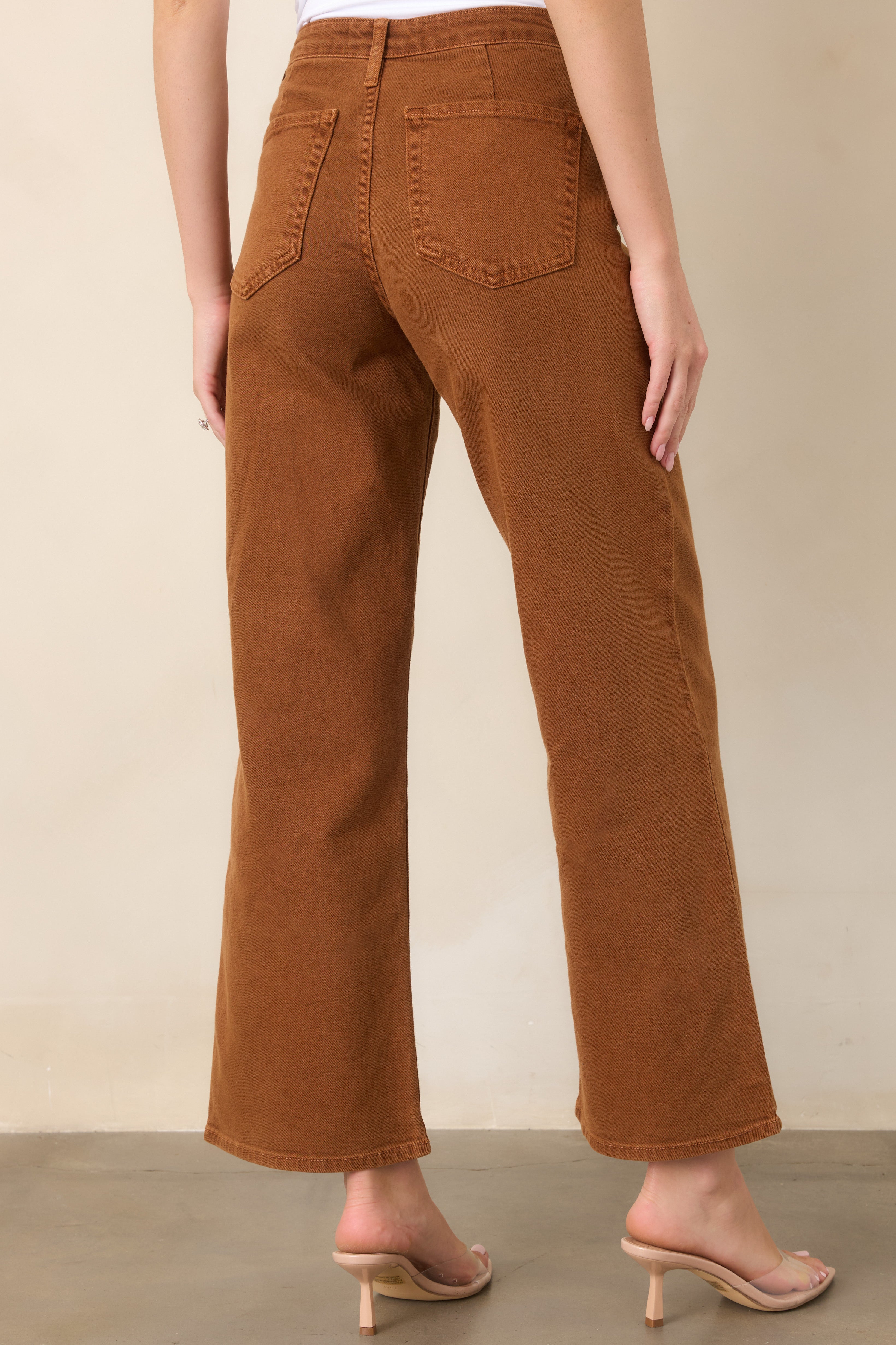 Rear view of the high-rise denim pants, featuring a clean waistband, belt loops, two back pockets, and relaxed wide legs.
