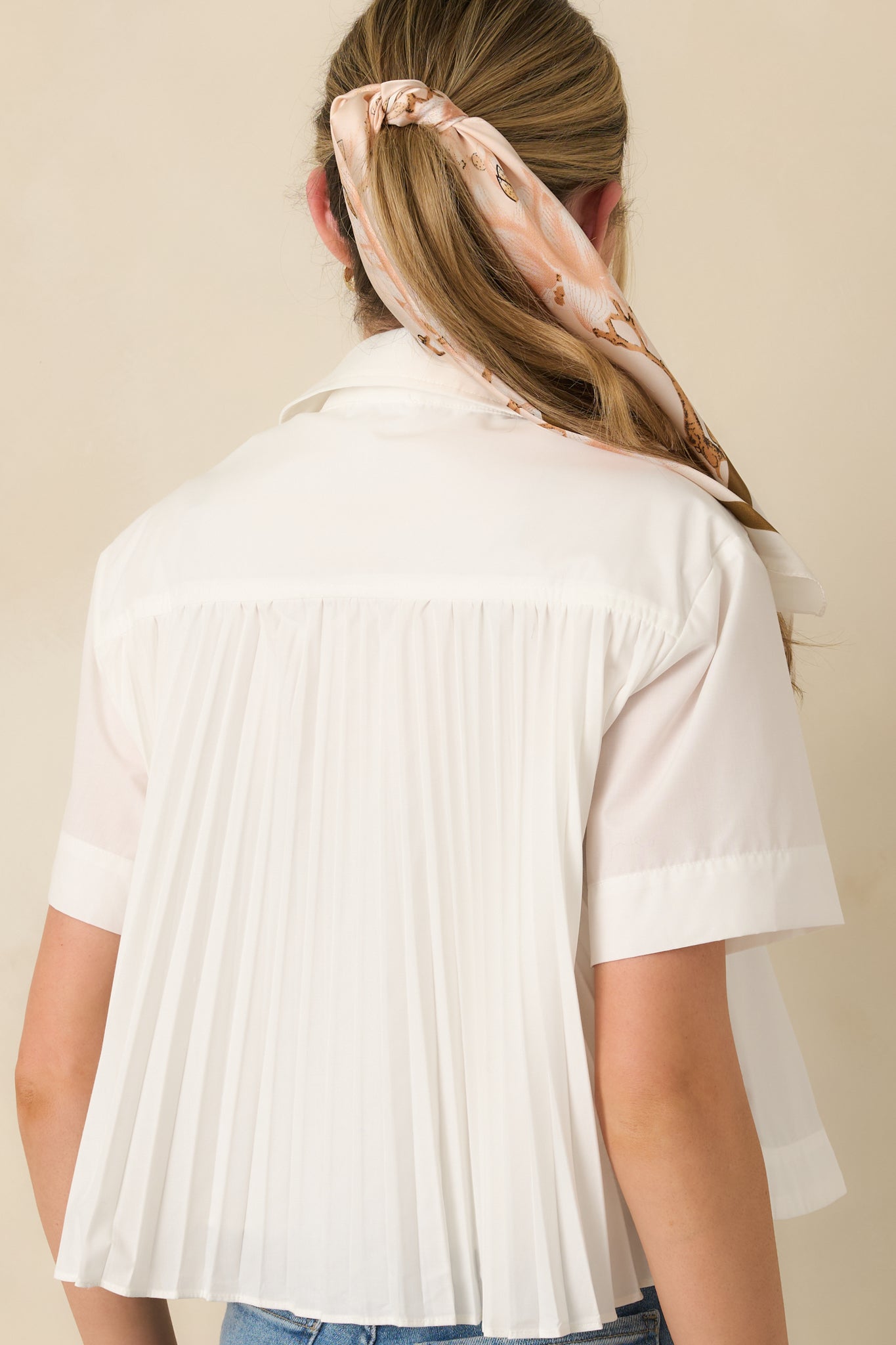 Rear view of the white blouse highlighting contrast pleated panel for added movement and dimension.