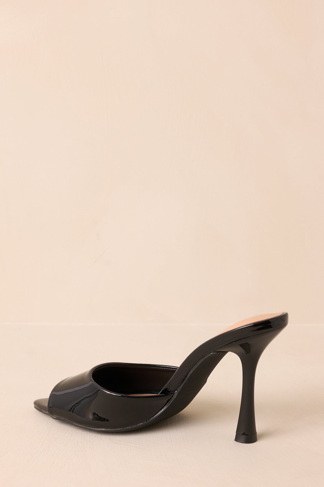 Rear view of black mule heels highlighting stiletto heel and open-back design.