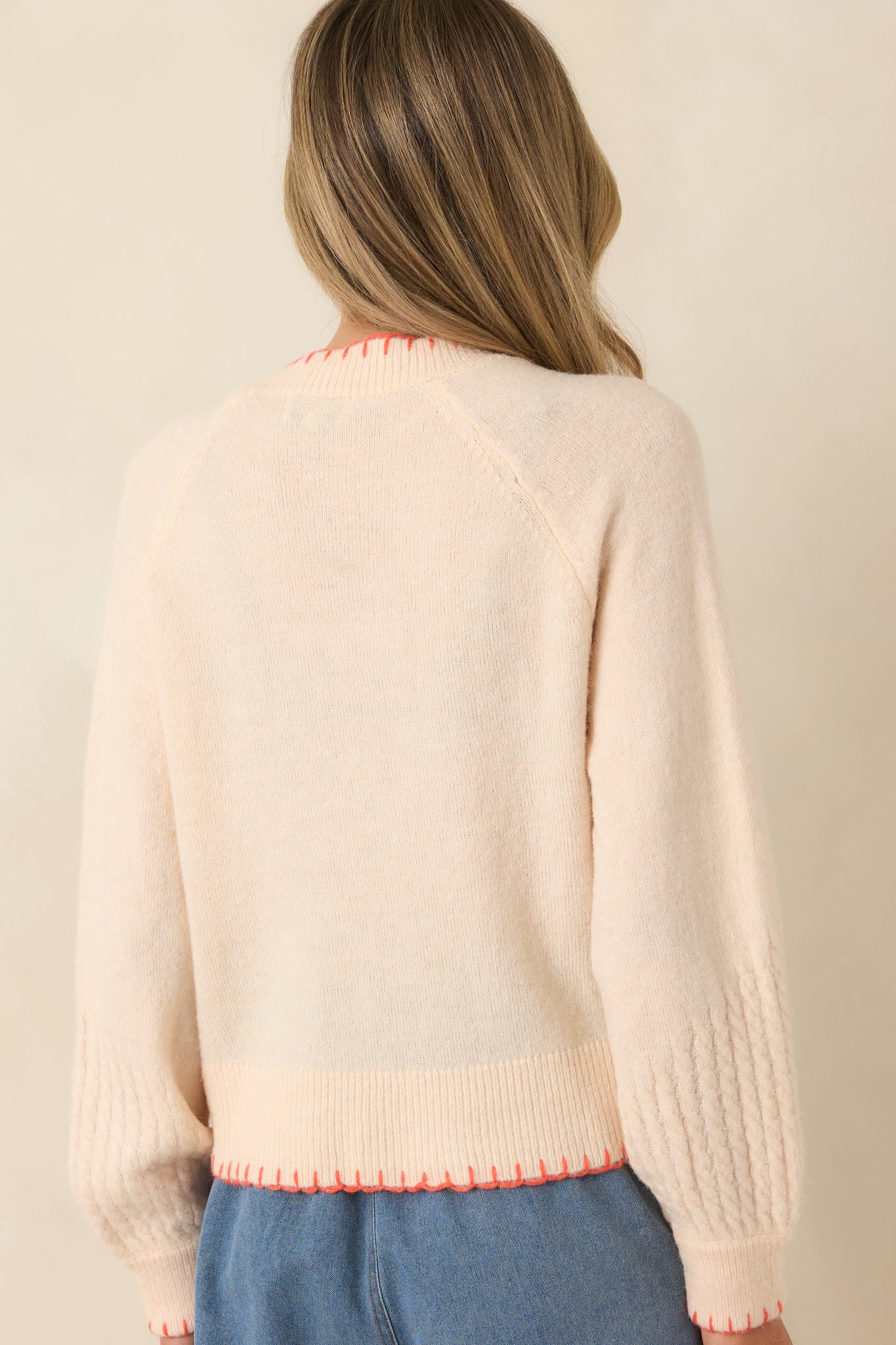 Rear view of ivory cardigan with relaxed fit and contrast stitching at hem.