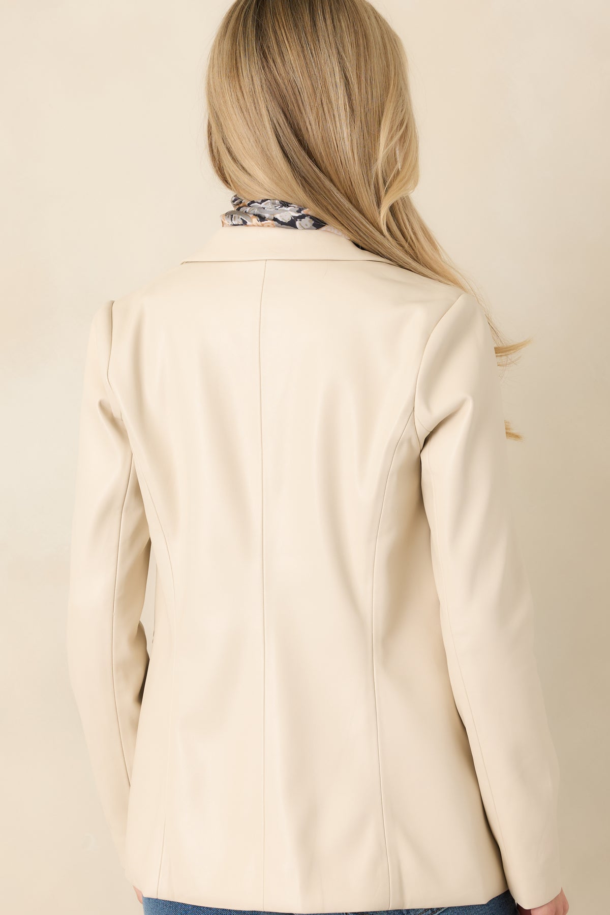 Rear view of the ivory faux leather blazer highlighting its curved seams and tailored hip-length shape.