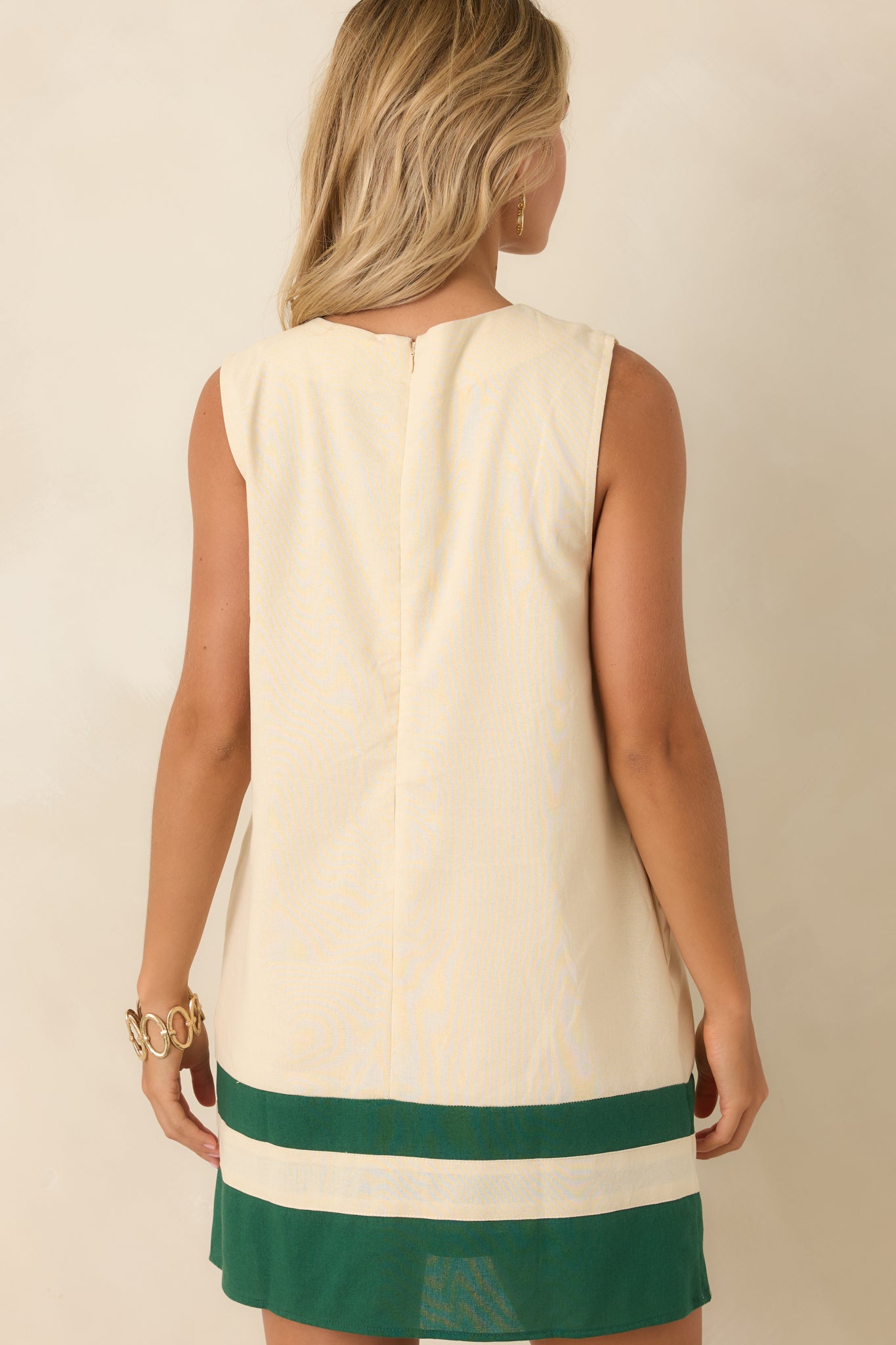 Rear view of the ivory floral mini dress featuring a hidden back zipper, sleeveless silhouette, smooth lining, and embroidered details.