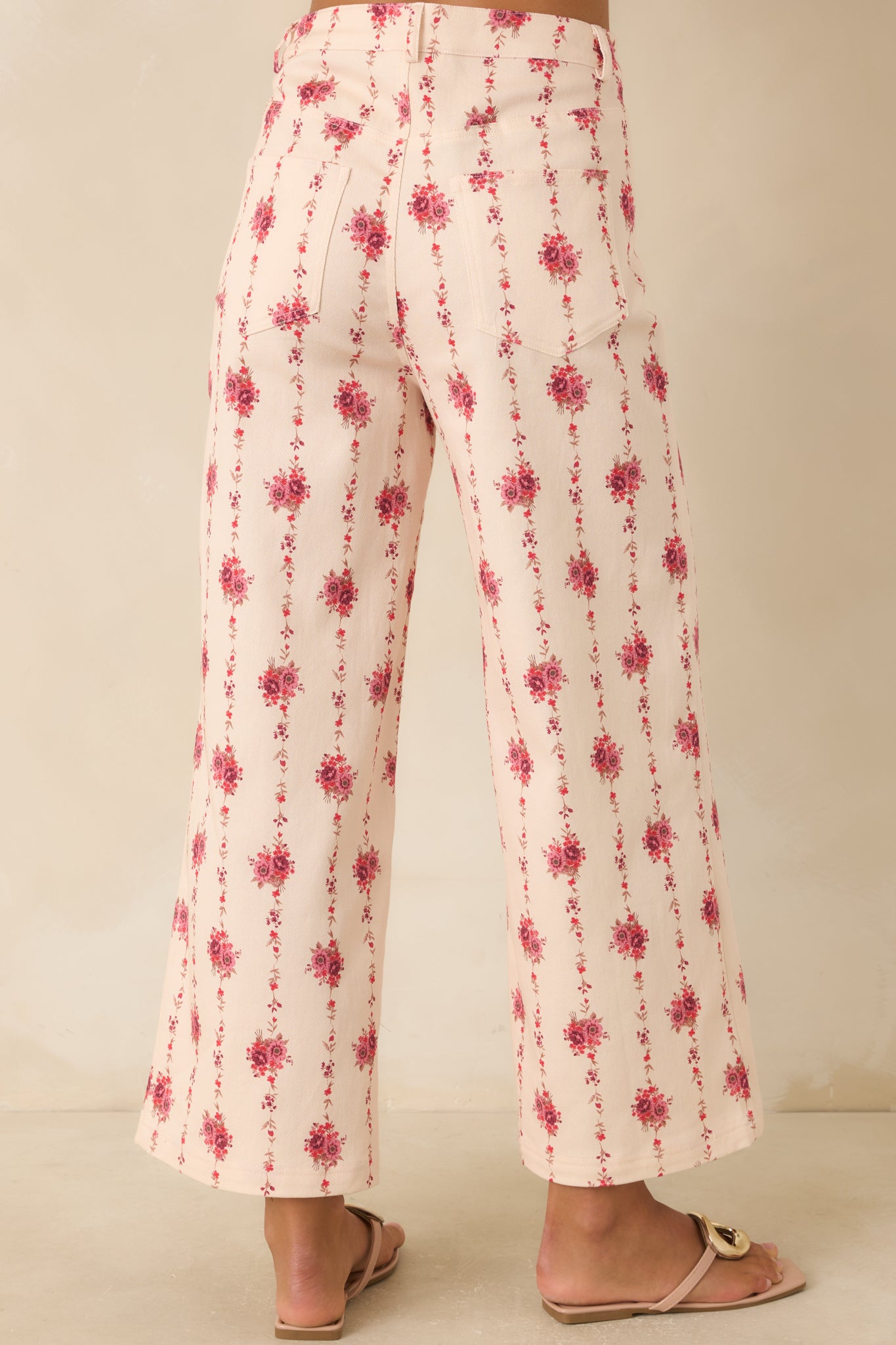 Rear view of the ivory floral pants featuring a high-rise fit, functional back pockets, belt loops, and vertical rose vine pattern.