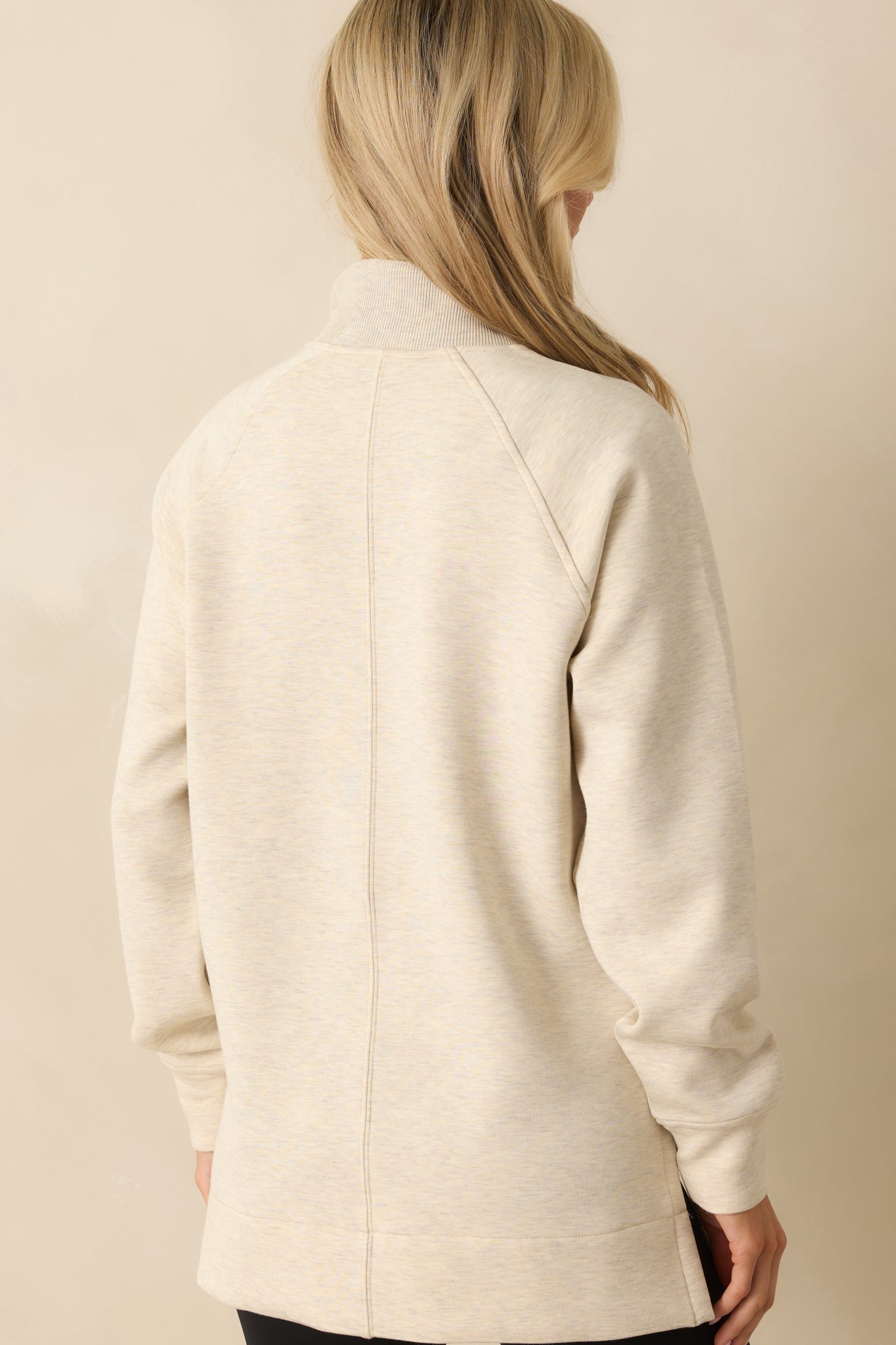 Rear view of the ivory pullover with tunic-length drape and relaxed silhouette.