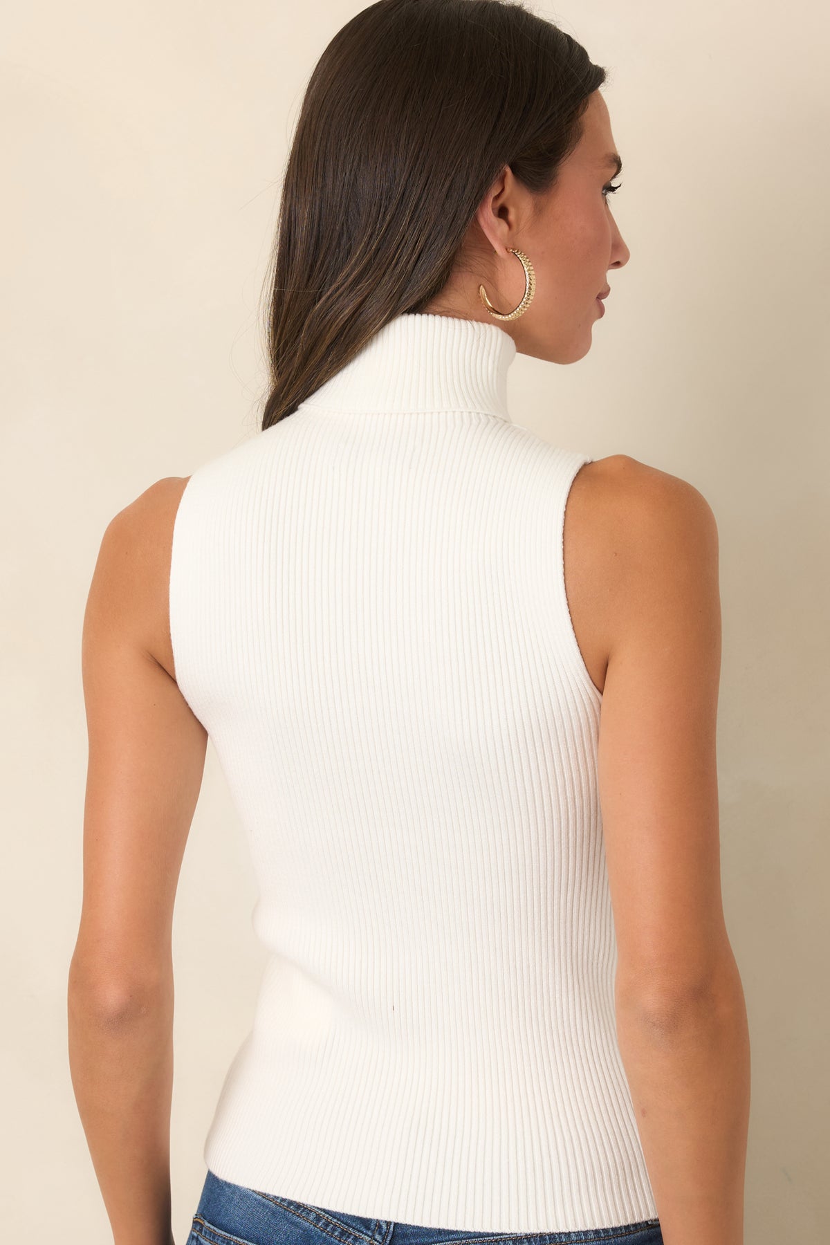 Rear view of the ivory ribbed knit top with a fitted silhouette and hip-length hem.