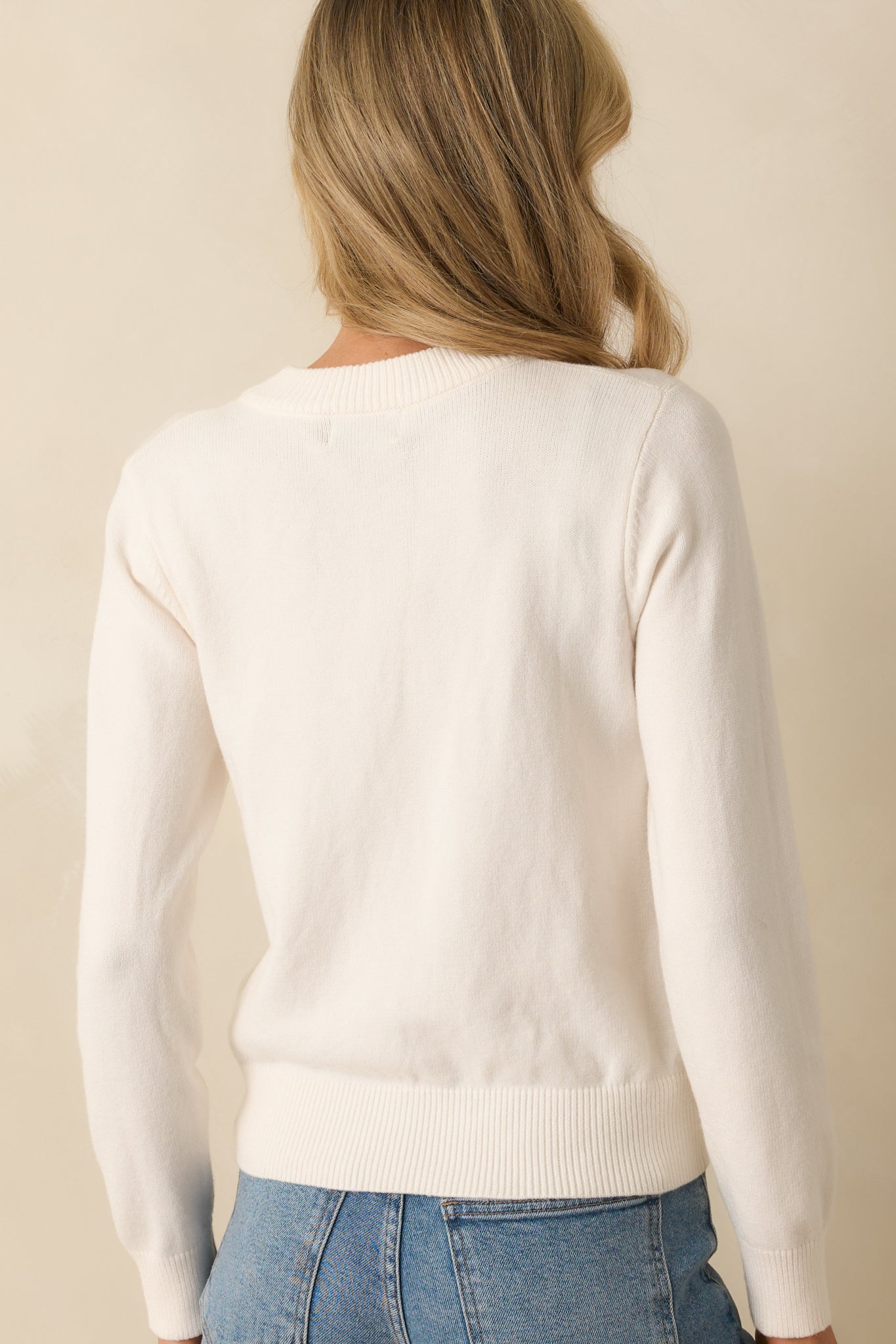 Rear view of the ivory sweater showing long sleeves, relaxed fit, and ribbed hem.