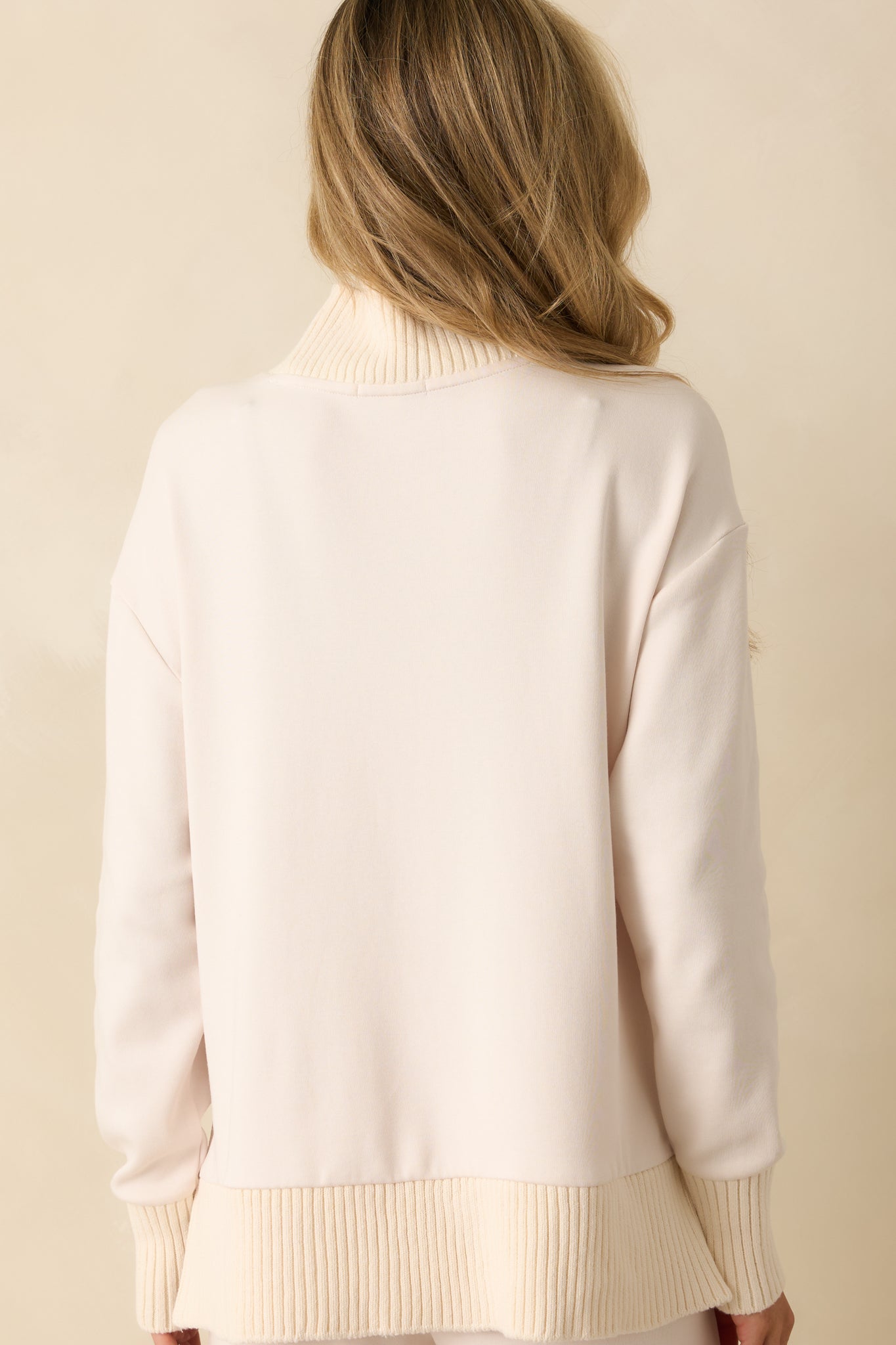 Rear view of ivory sweater showing ribbed trim, long sleeves, and relaxed silhouette.