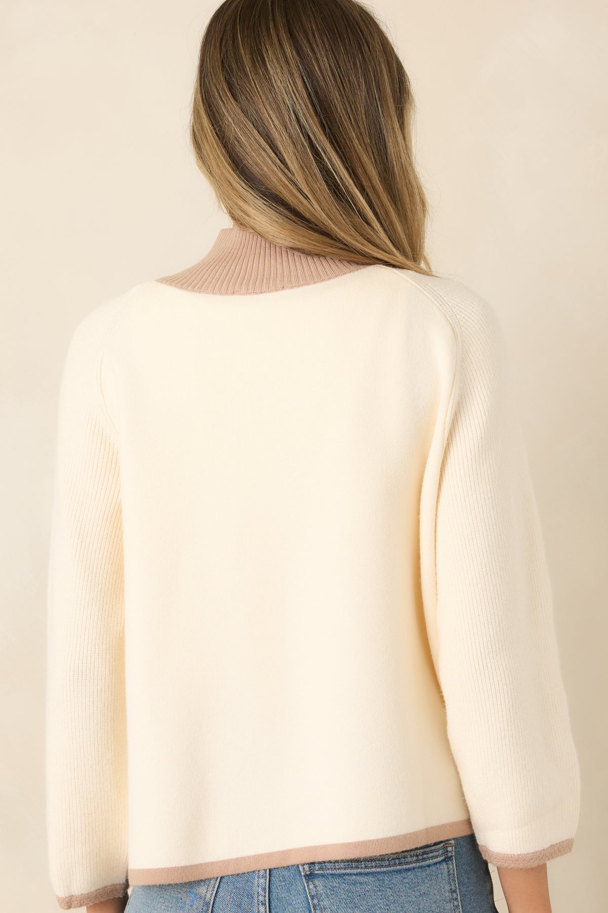 Rear view of the ivory cardigan showcasing the relaxed knit silhouette, taupe contrast trim, ribbed hem and cuffs, and clean back design.