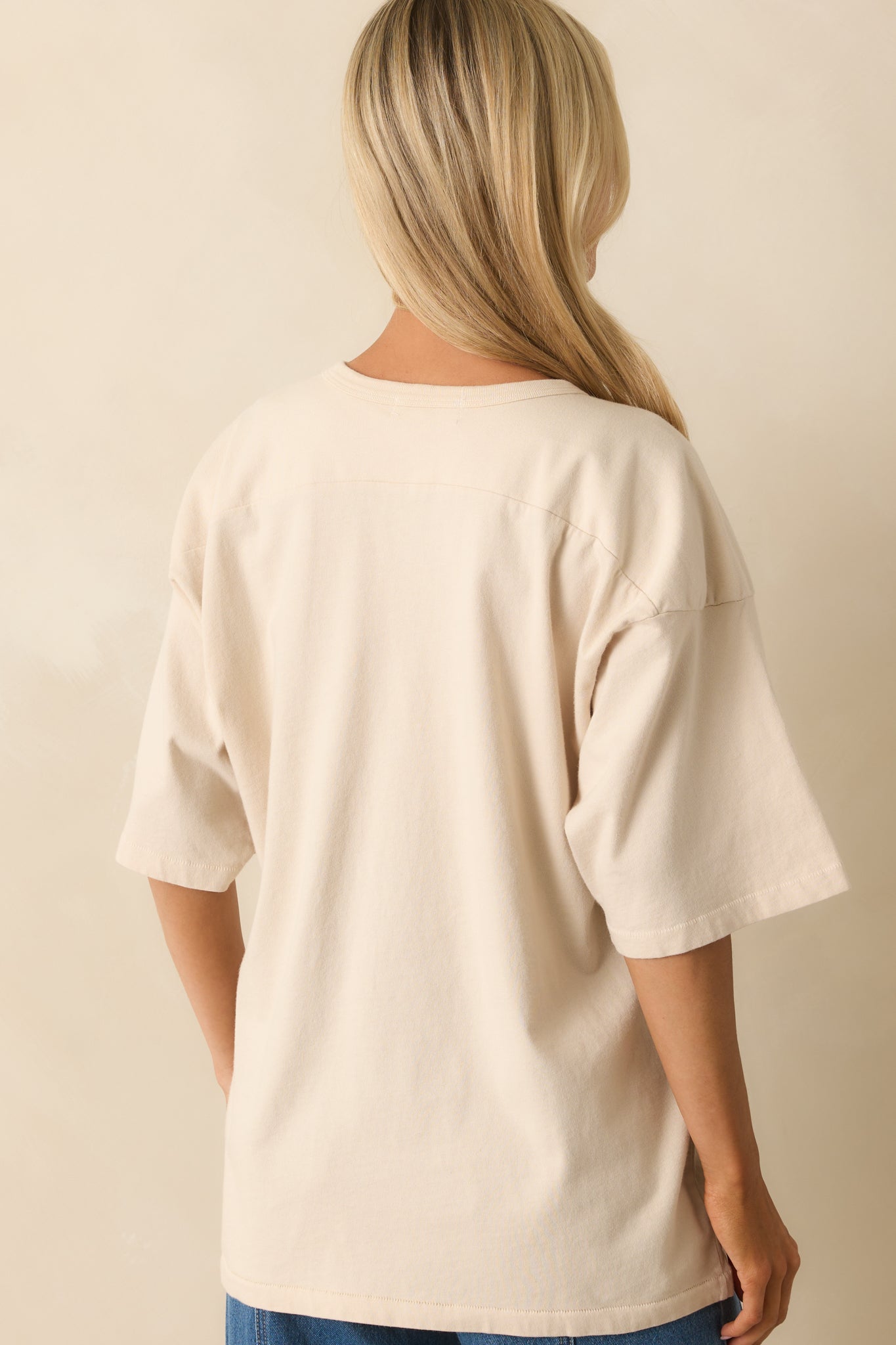 Rear view of ivory oversized T-shirt showing solid ivory fabric, relaxed fit, and dropped shoulders.