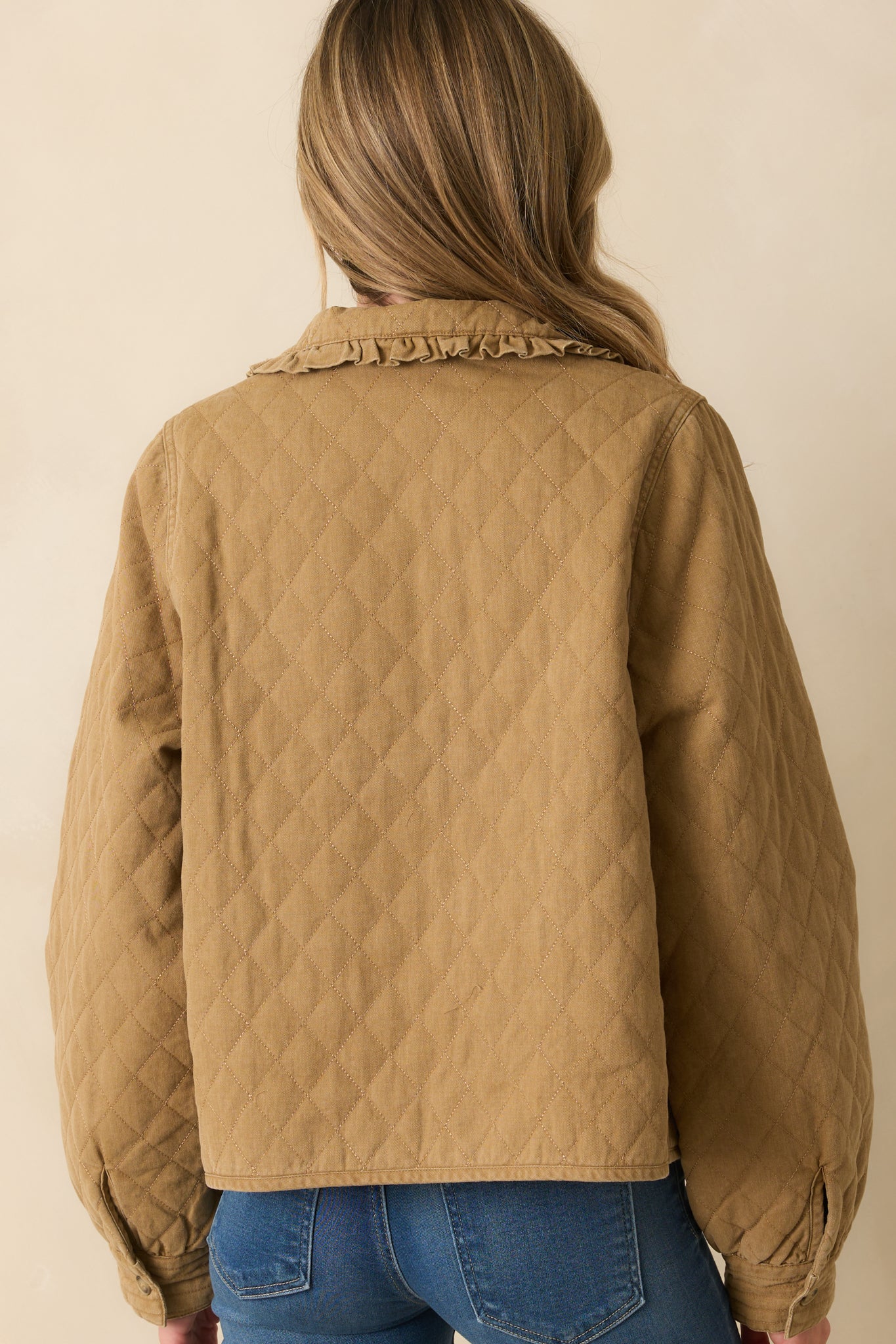 Rear view of the khaki brown quilted jacket showing straight hemline and puffed shoulder silhouette.