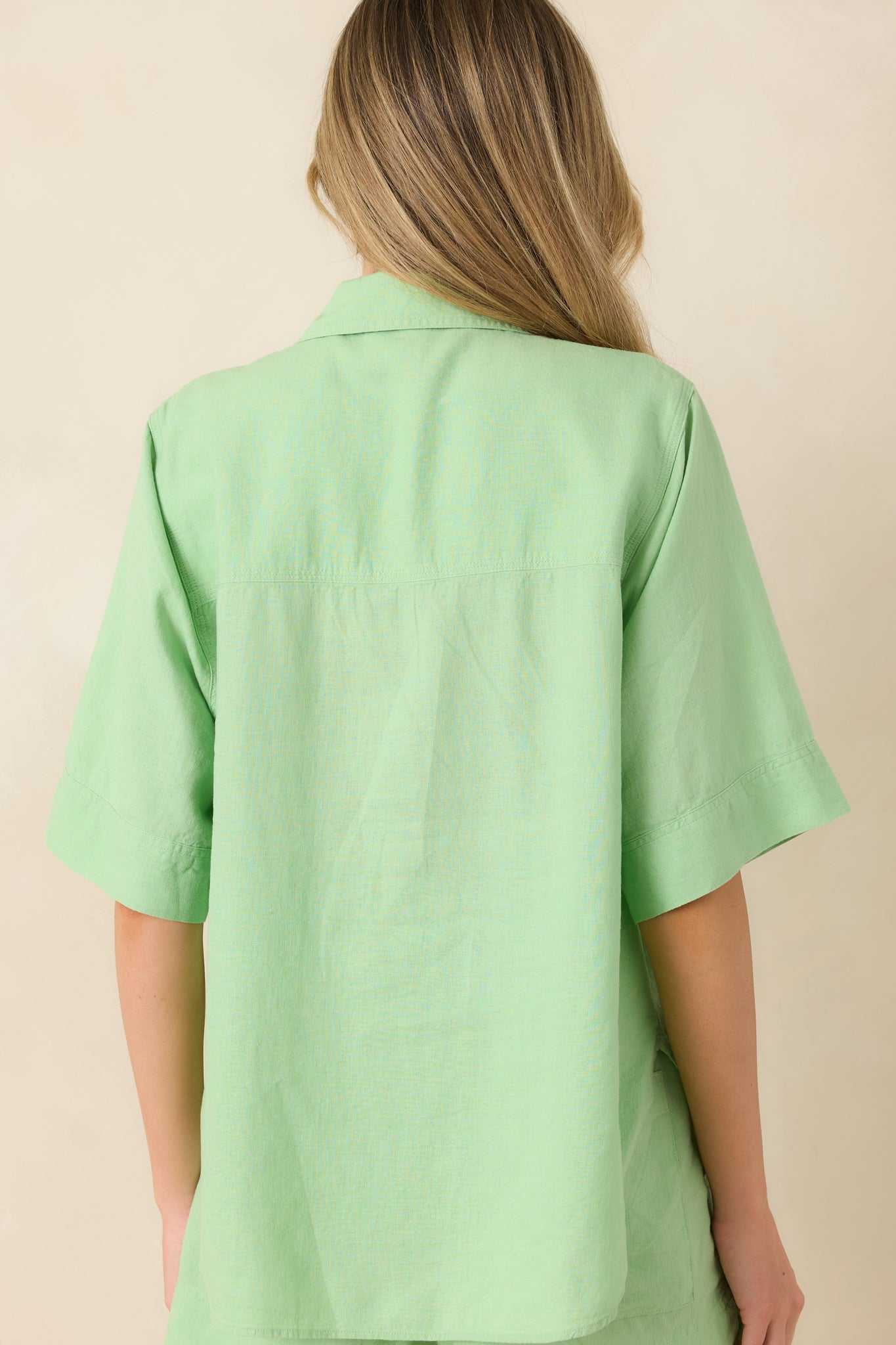 Rear view of light green top with relaxed drape and clean finish.