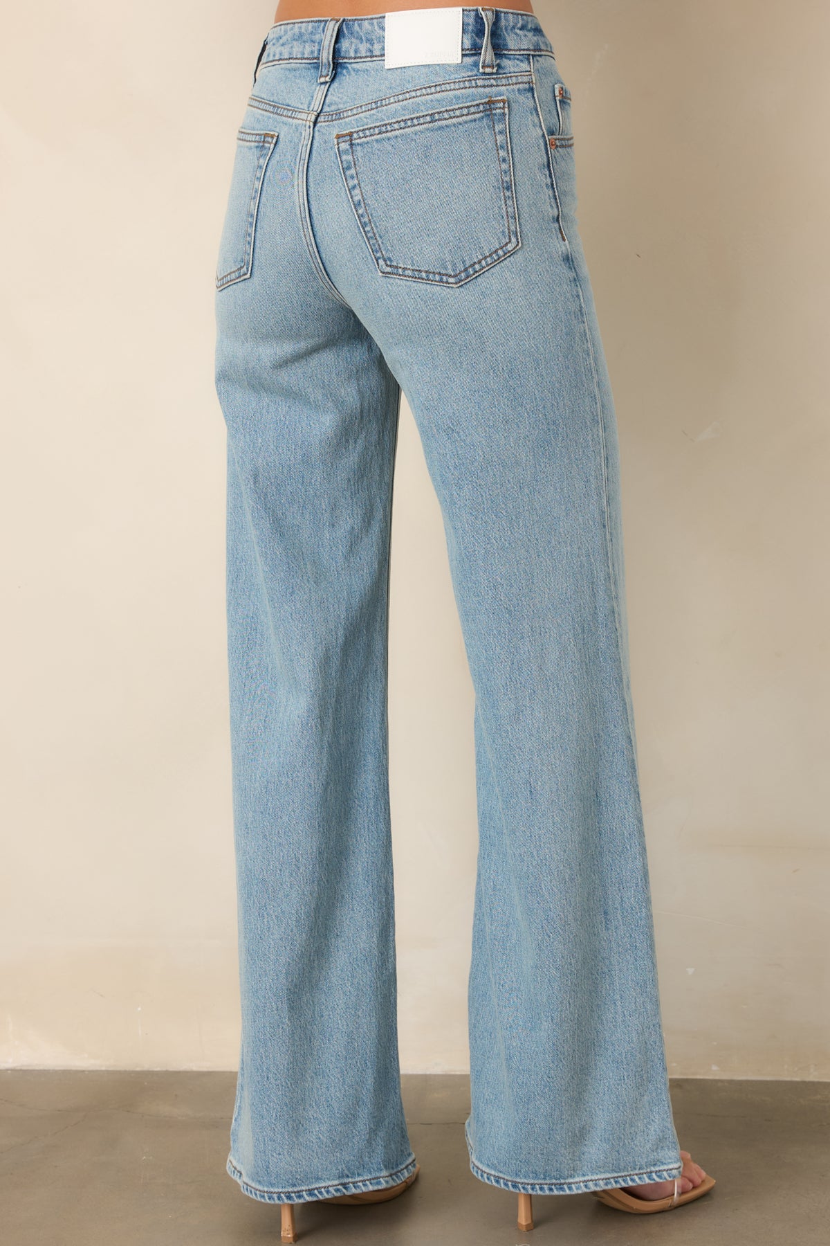 Rear view of the light-wash jeans showing the mid-rise waist, belt loops, and back pockets.