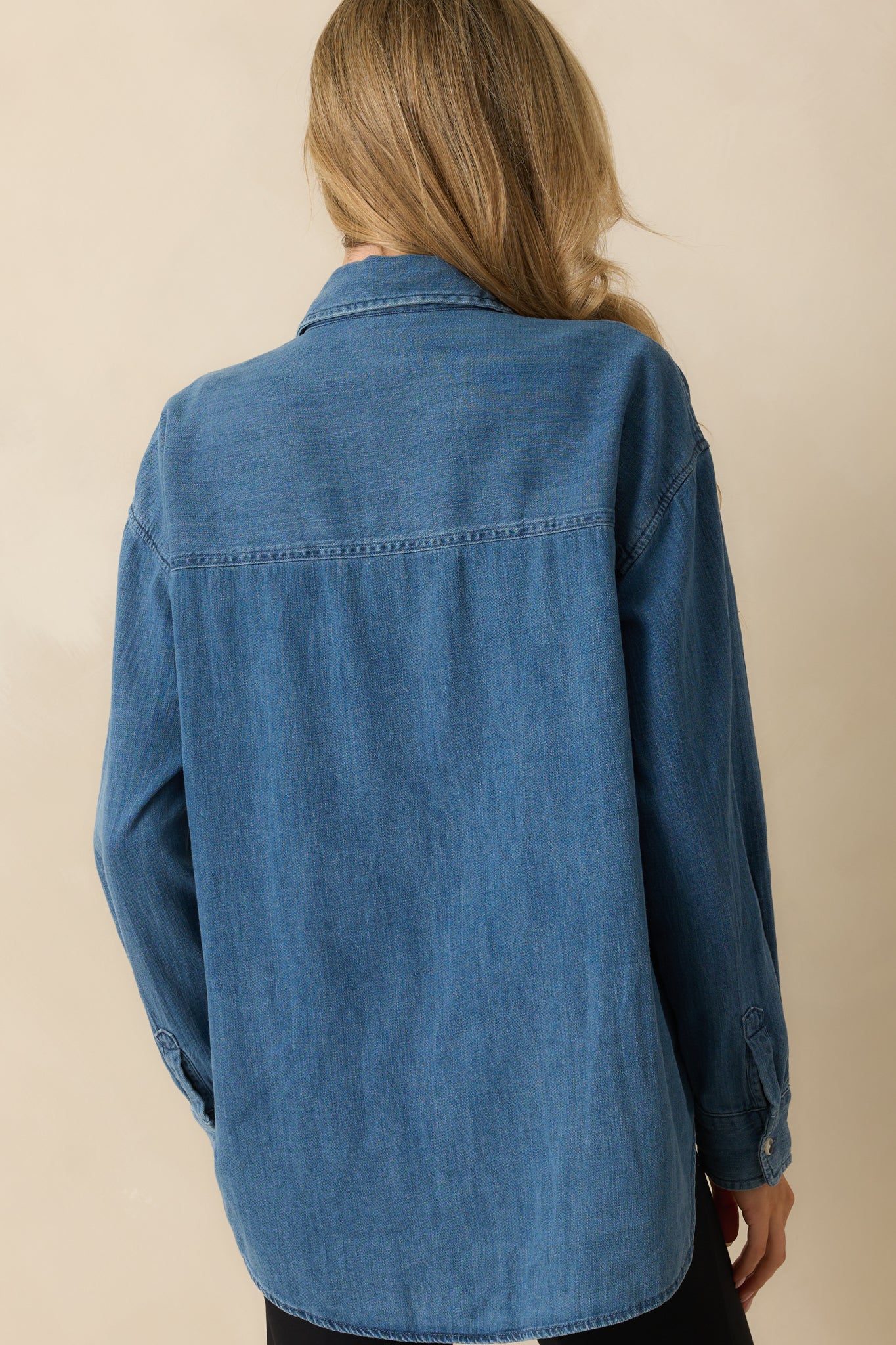 Rear view of the medium wash top showing long sleeves and relaxed fit.