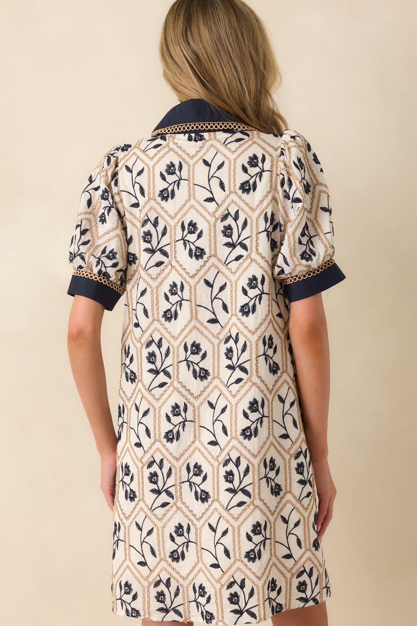 Rear view of the mini dress, showing the puff sleeves, embroidered pattern, and navy collar detail.