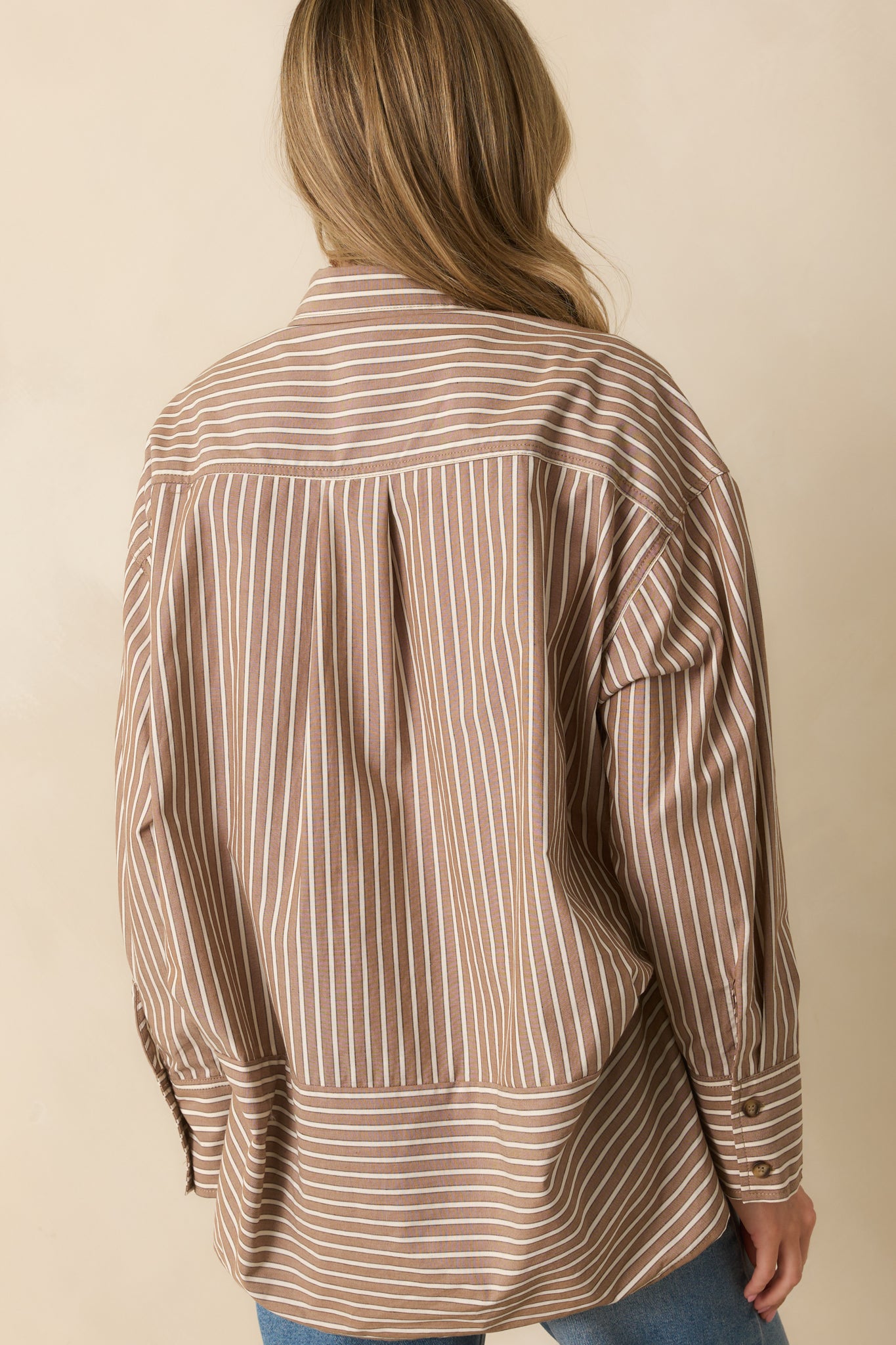 Rear view of mocha brown striped shirt with long sleeves and scoop bottom hem.