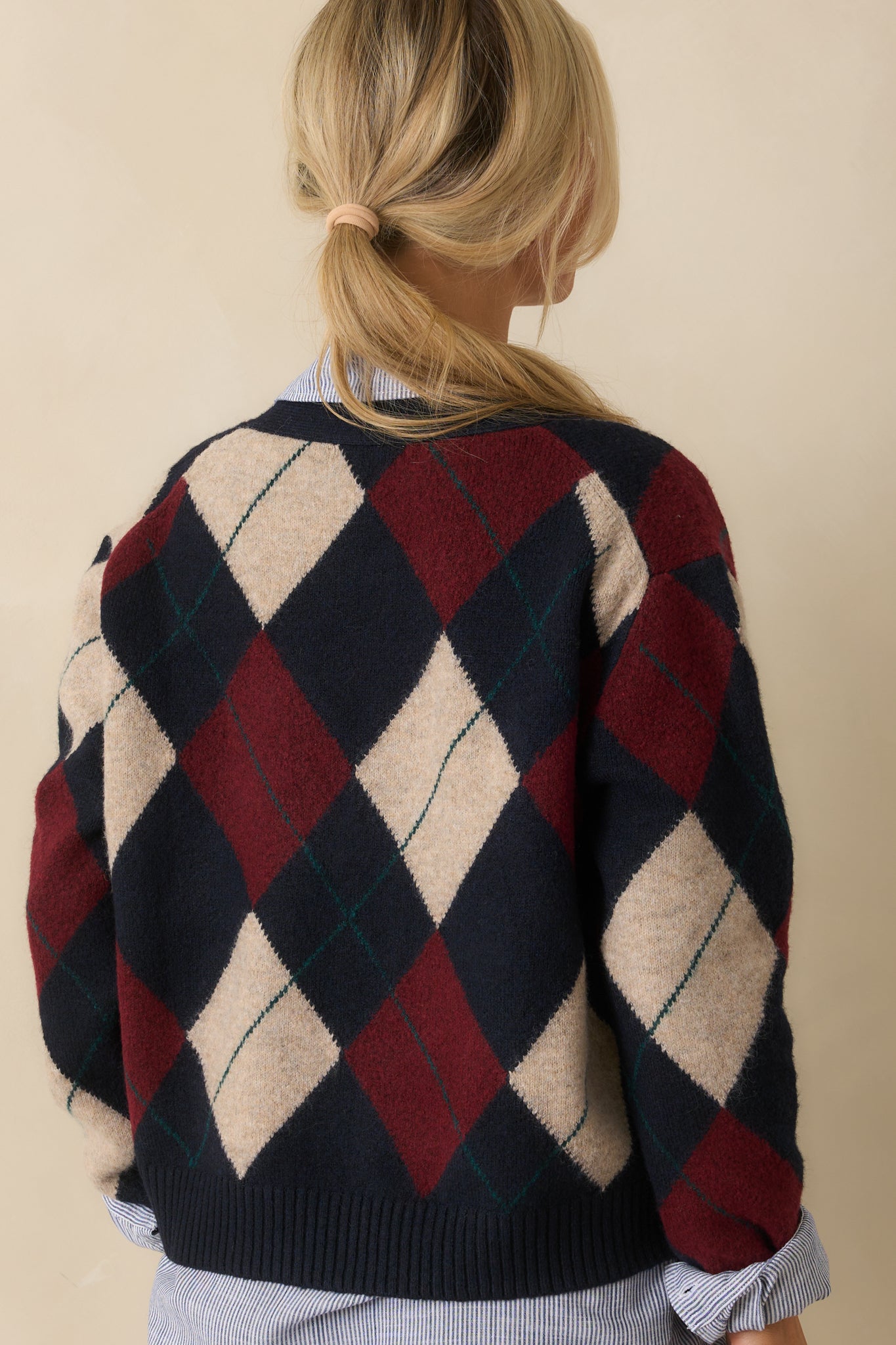 Rear view of the navy cardigan with long sleeves and argyle pattern across the back.