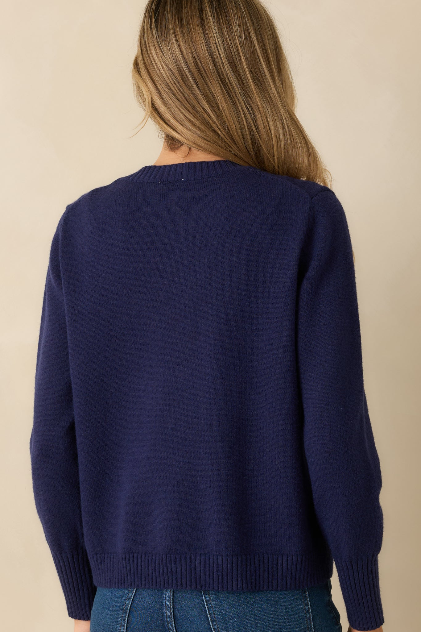 Rear view of the navy cardigan showing long sleeves, ribbed hem, and relaxed fit silhouette.

