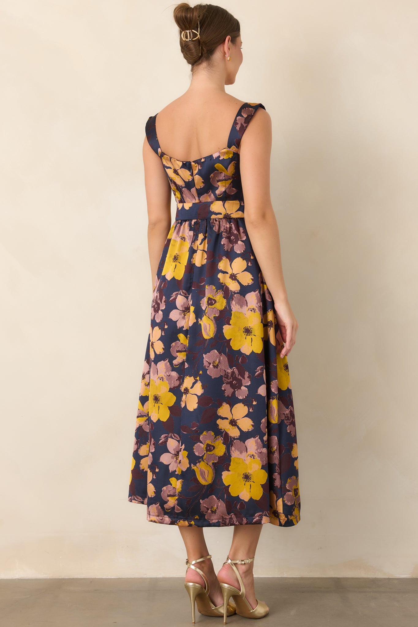 Rear view of the navy floral midi dress showcasing the wide straps, defined tie waist, and gathered skirt.