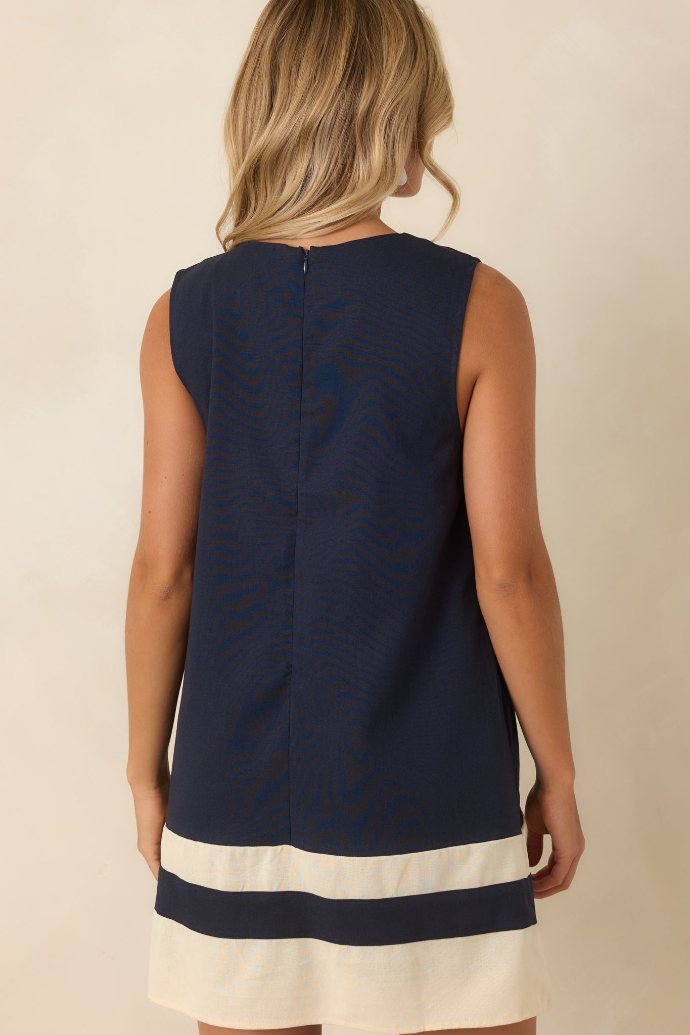 Rear view of the navy floral mini dress featuring a hidden back zipper, sleeveless silhouette, smooth lining, and embroidered details.