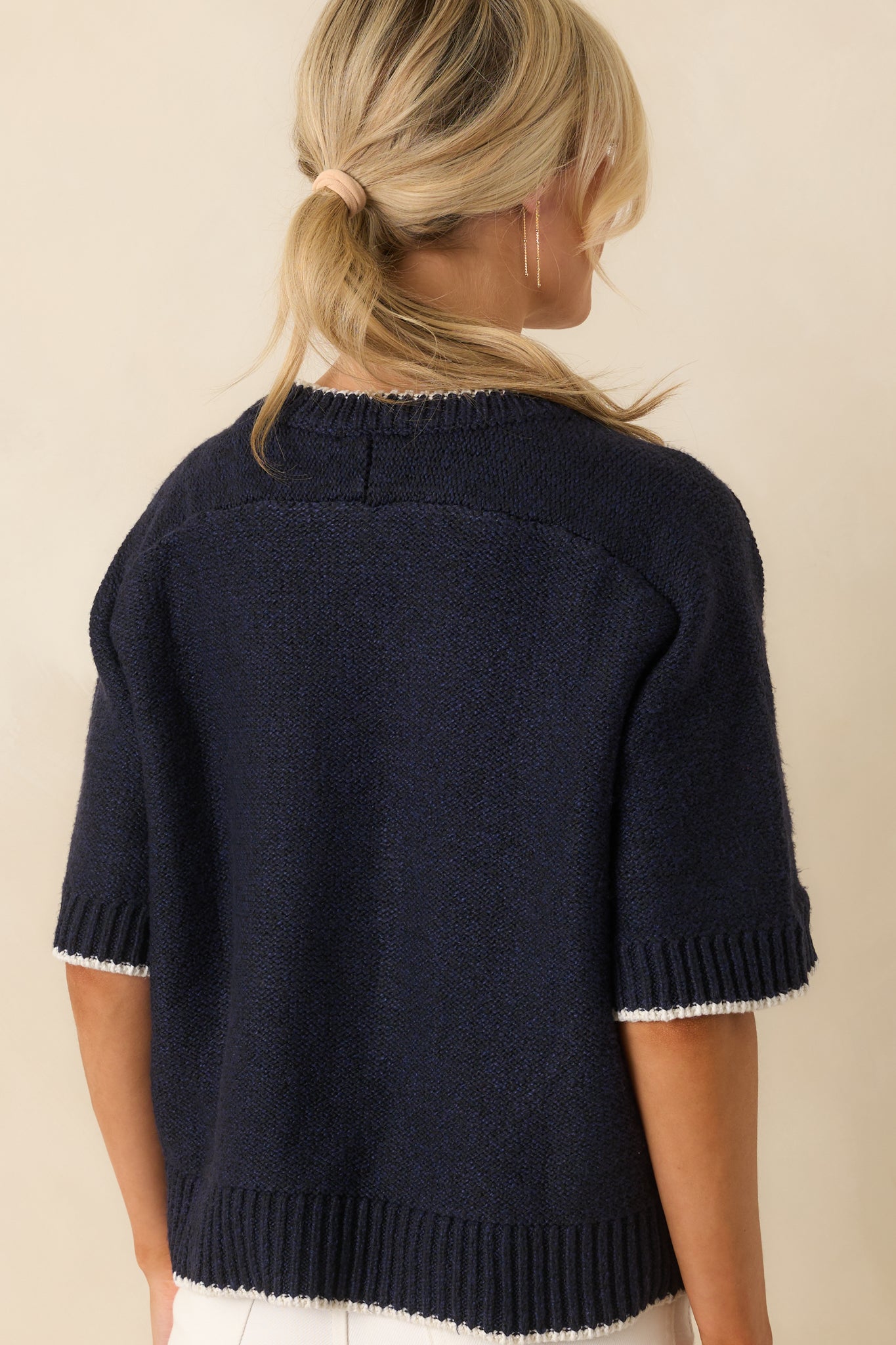A view from behind of navy oversized sweater with ivory contrast trim and ribbed hems.