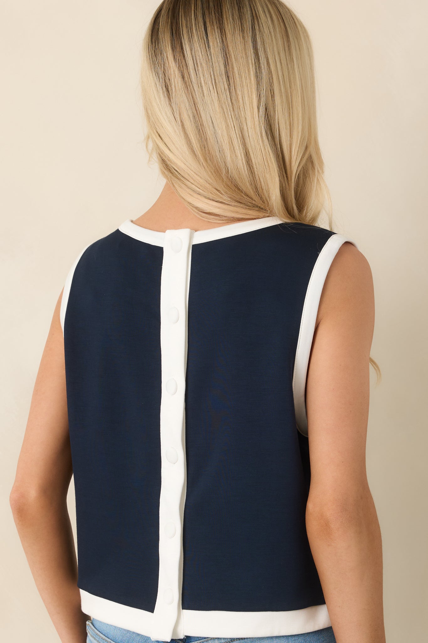 Rear view of the navy top with full button-back closure and subtle side slits.