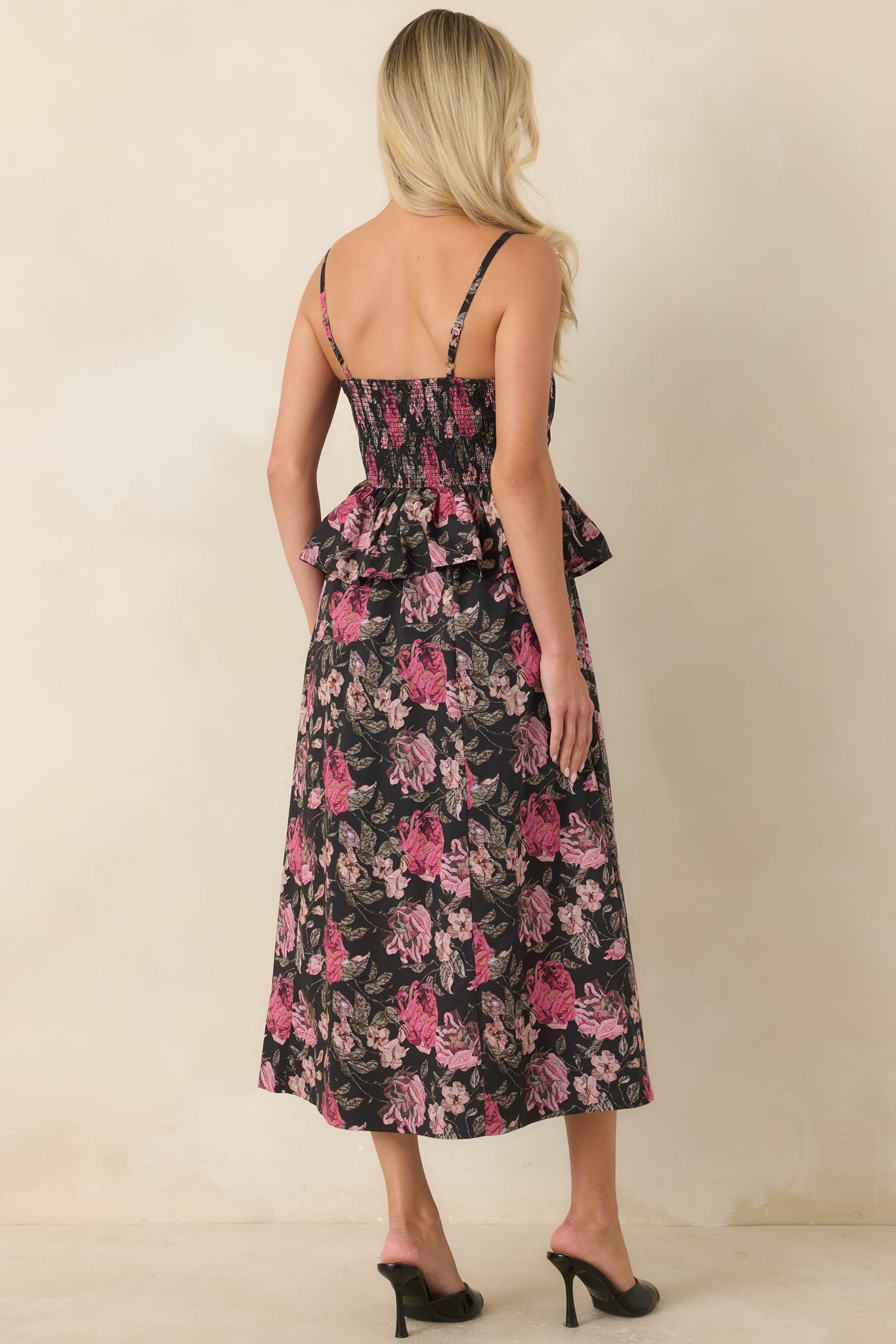 Rear view of the black midi dress showcasing the smocked back panel and flowing skirt.