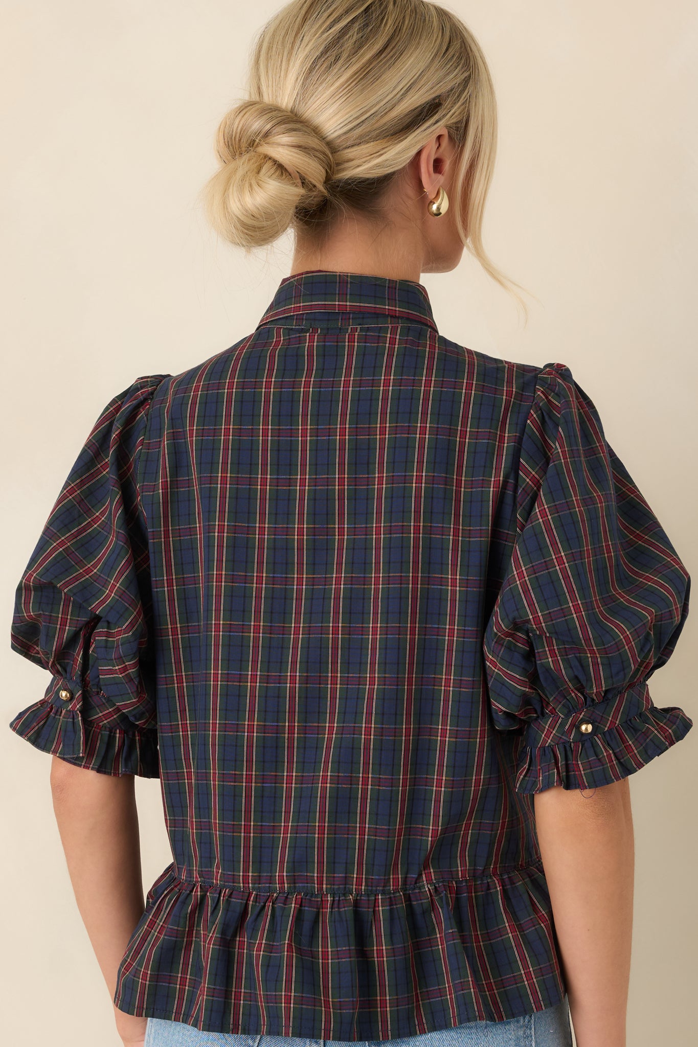 Rear view of the blouse showcasing the gathered peplum hem and smooth lined finish.