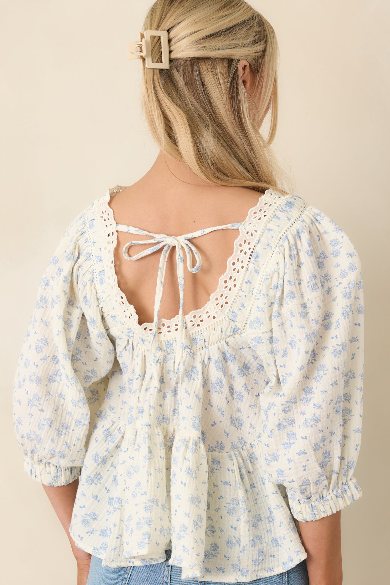 Rear view of blouse with subtle open detail, tie closure, and puffed sleeves.