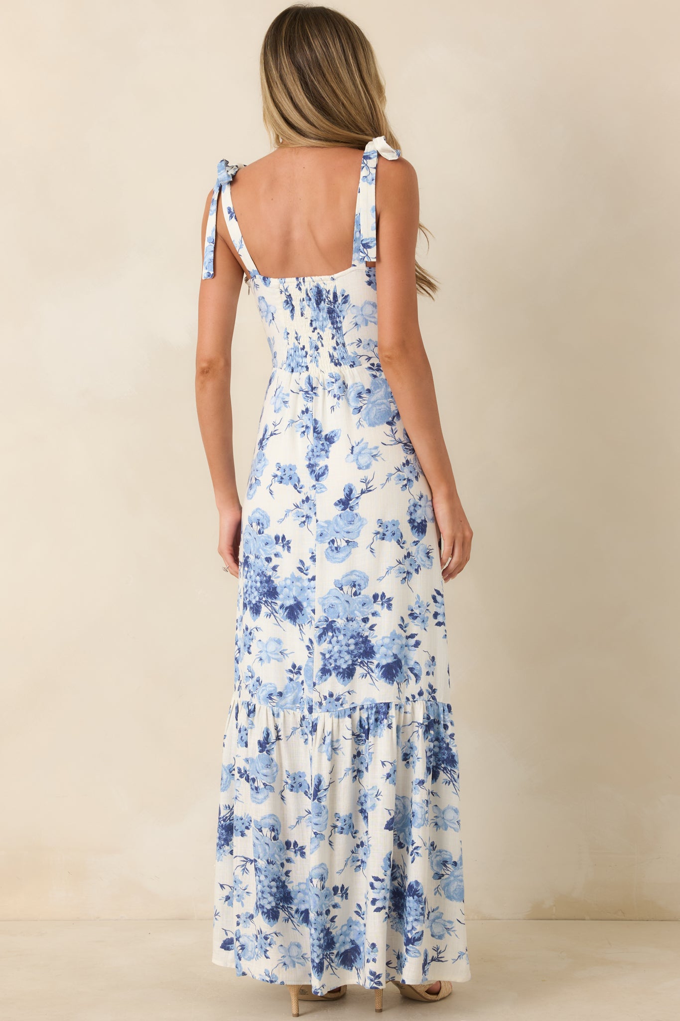 Rear view of blue floral midi dress with tie straps and flowing tiered skirt.

