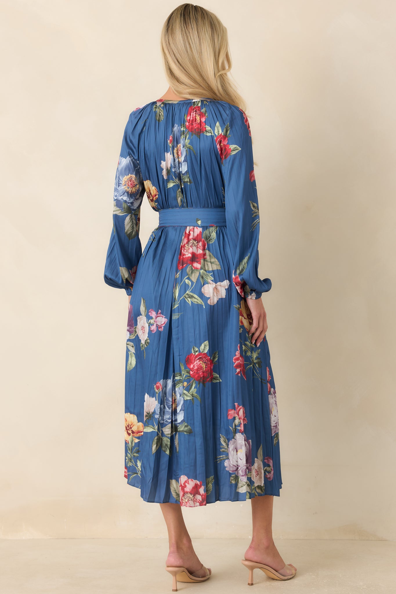Rear view of the blue midi dress highlighting the all-over pleating, balloon sleeves, and flowing skirt.