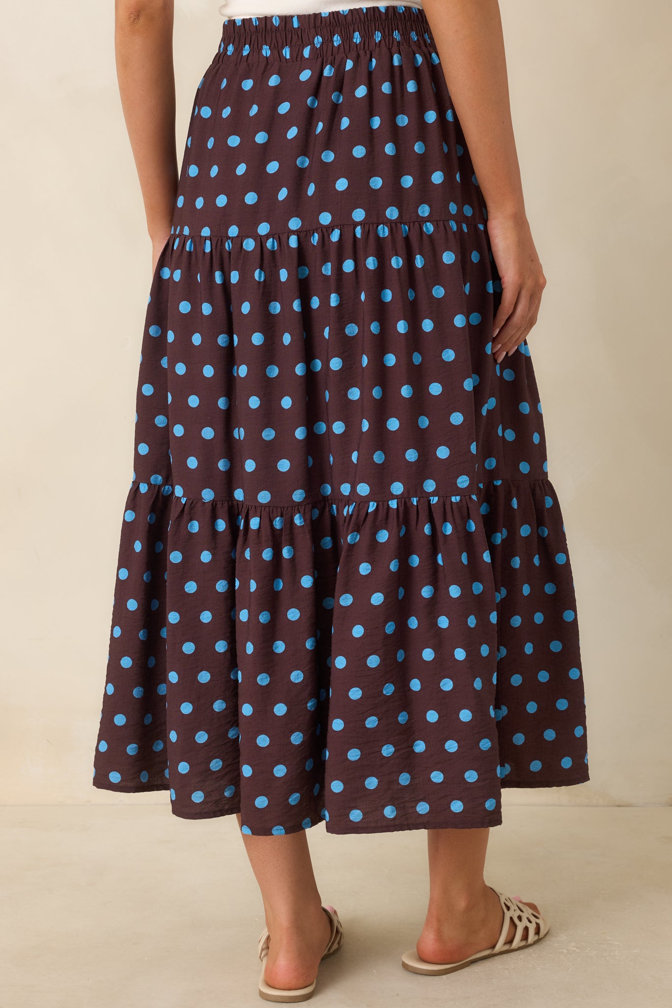 Rear view of the brown polka dot skirt showcasing the smocked waistband, flowing shape, and gathered tiered design.