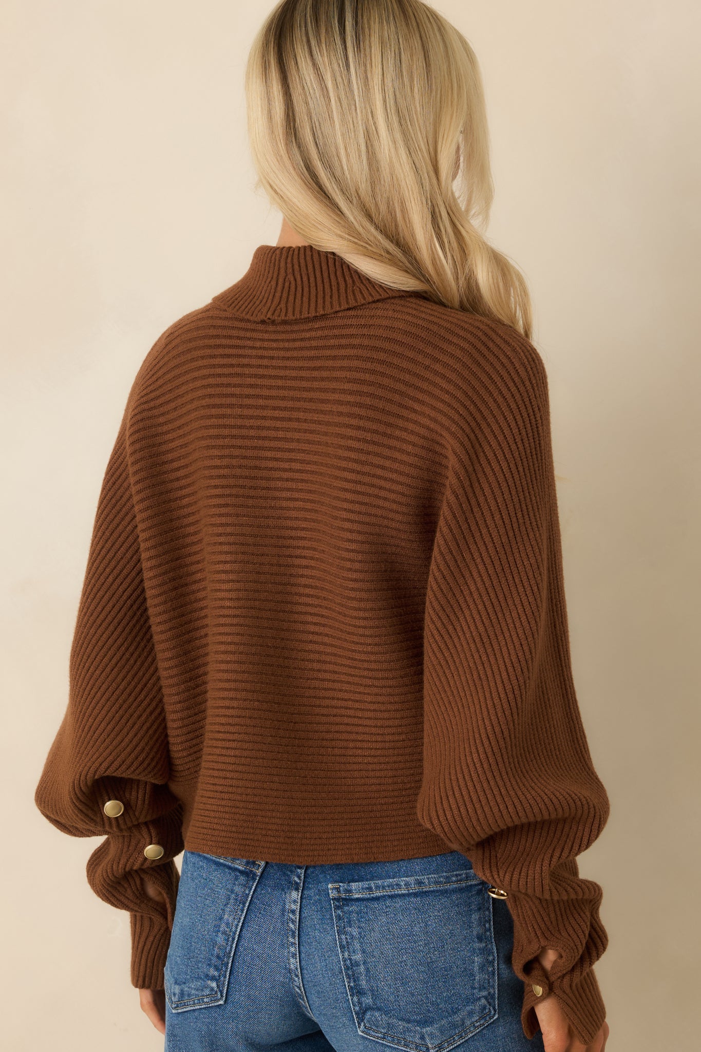 Rear view of brown ribbed sweater showing relaxed batwing fit and cropped hem.