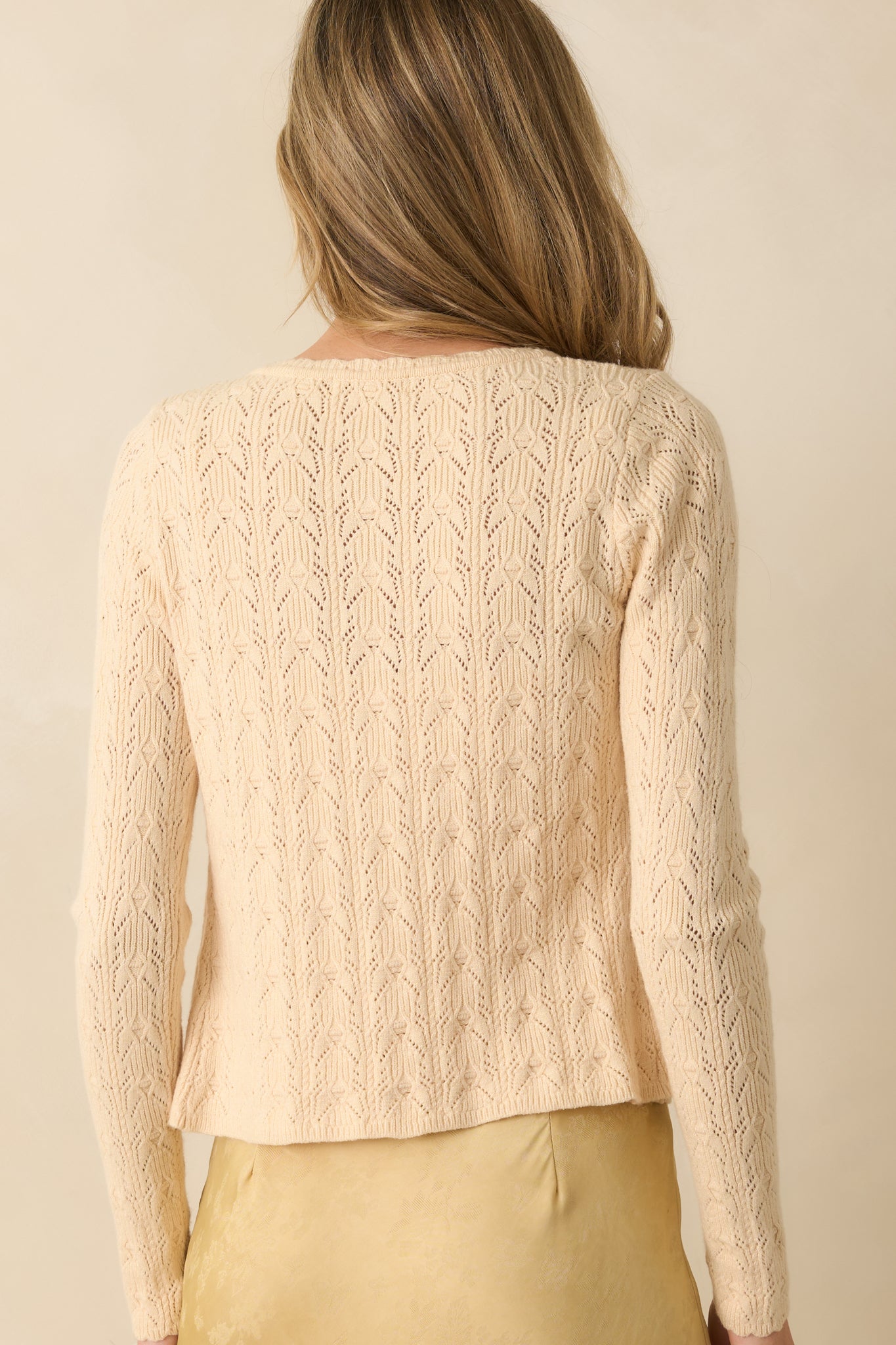 Rear view of ivory cardigan highlighting the cropped length and textured pointelle knit fabric.