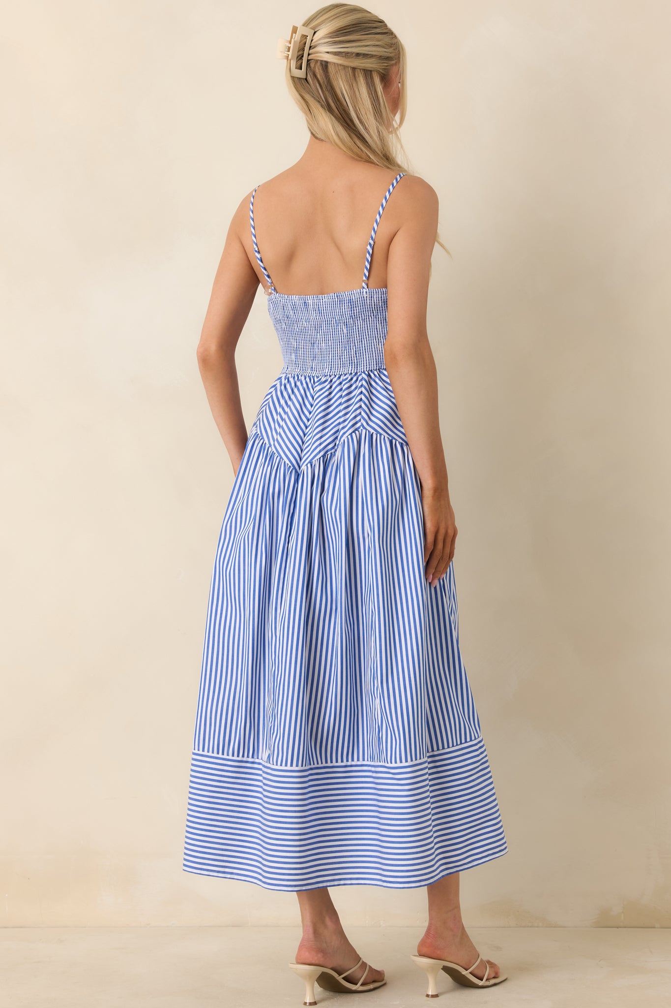 Rear view of dress with smocked back, slim straps, and flowing midi skirt.