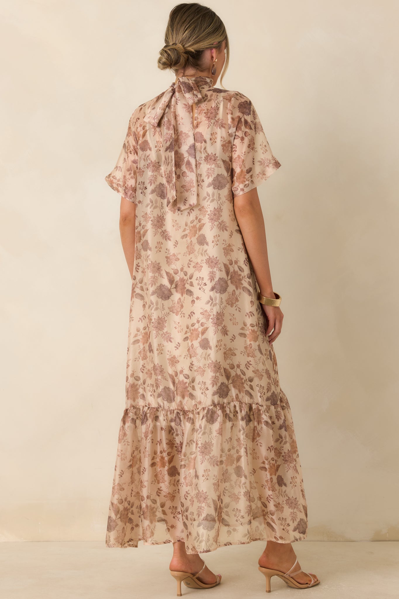 Rear view of the floral maxi dress highlighting the tied mock neckline, flowing overlay, and layered A-line skirt.