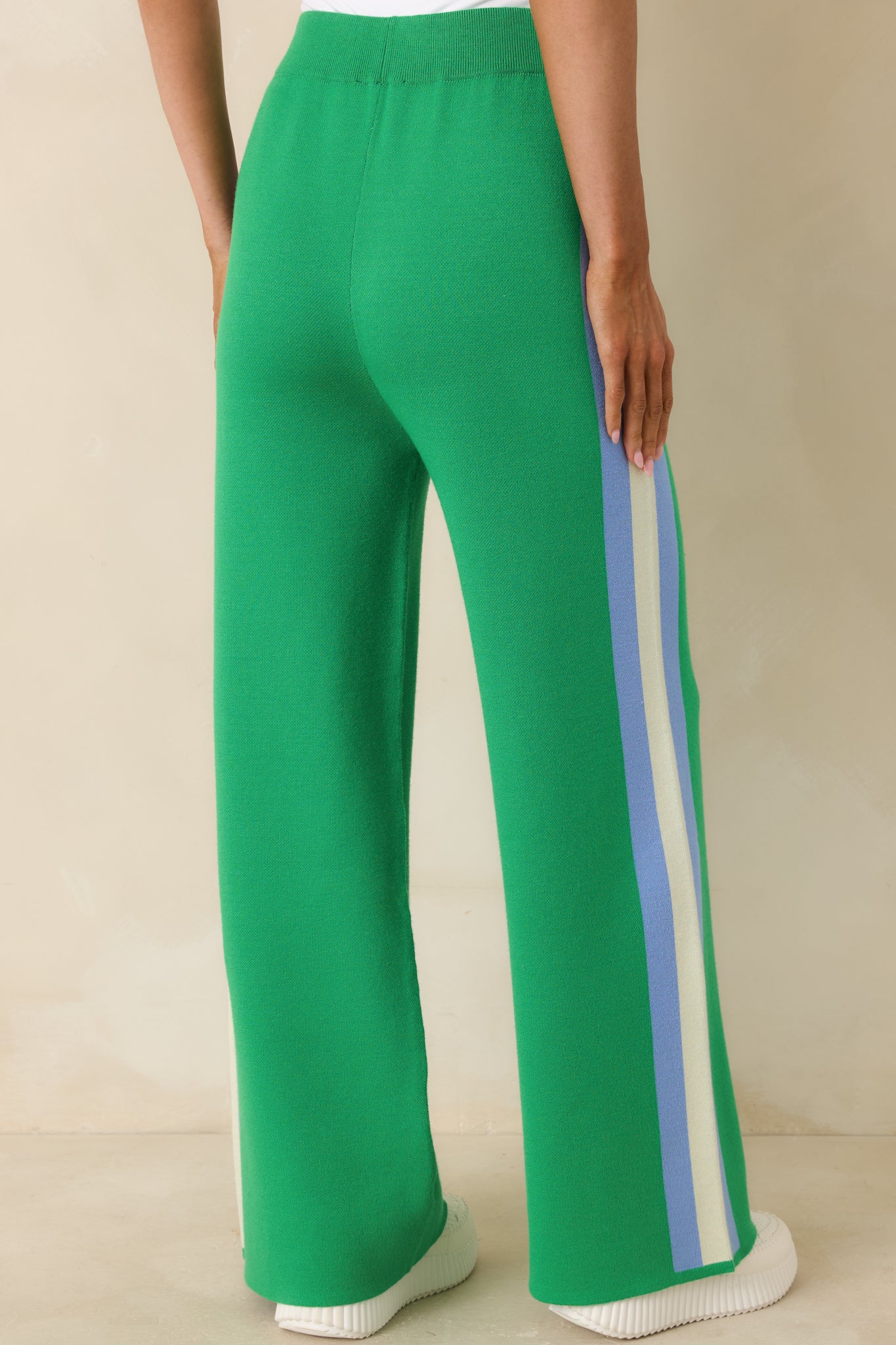 Rear view of green knit pants with high-rise waistband, wide-leg fit, and side stripe.