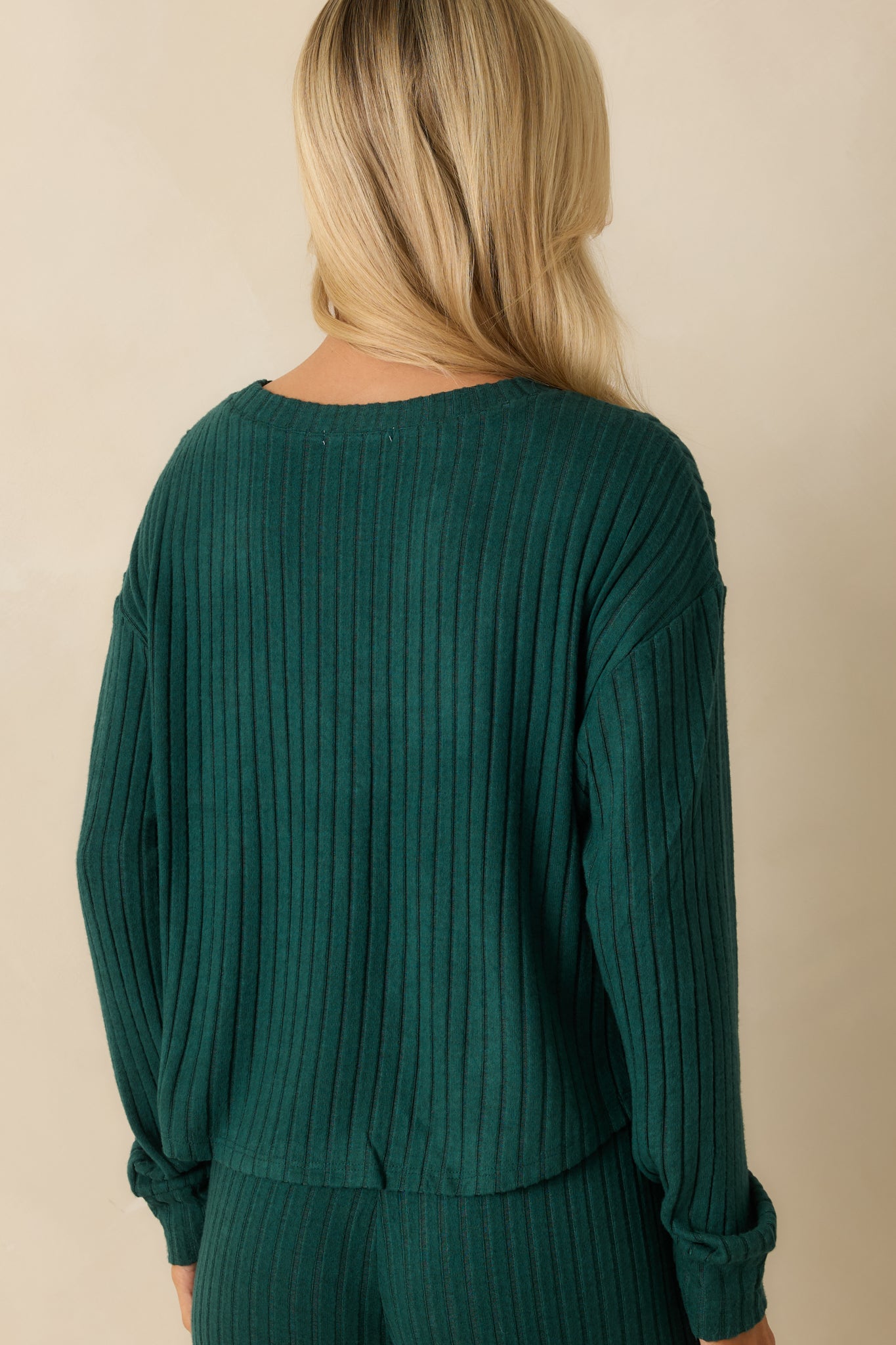 Rear view of green long-sleeve top with relaxed fit, crew neckline, and smooth ribbed knit finish.